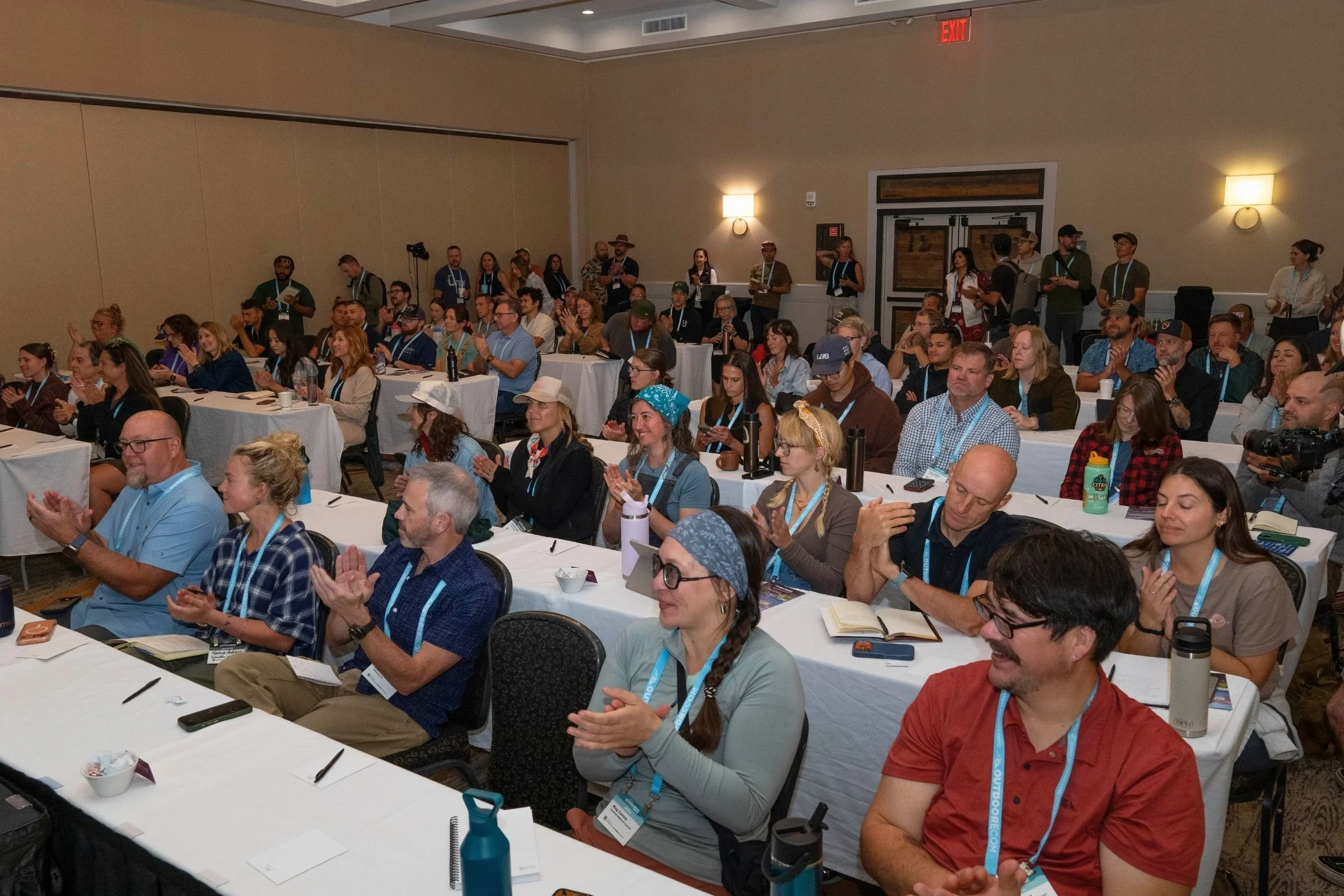 A large group sits at tables inside a room during the 2026 Outdoor Media Summit.