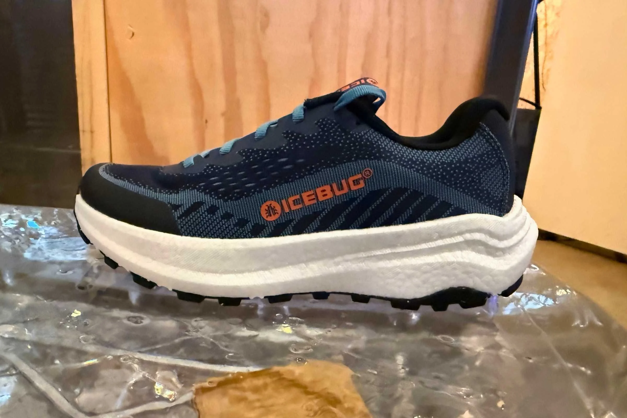 A close-up of an Icebug running shoe featuring a thick cushioned midsole and studded outsole designed for traction on icy surfaces.