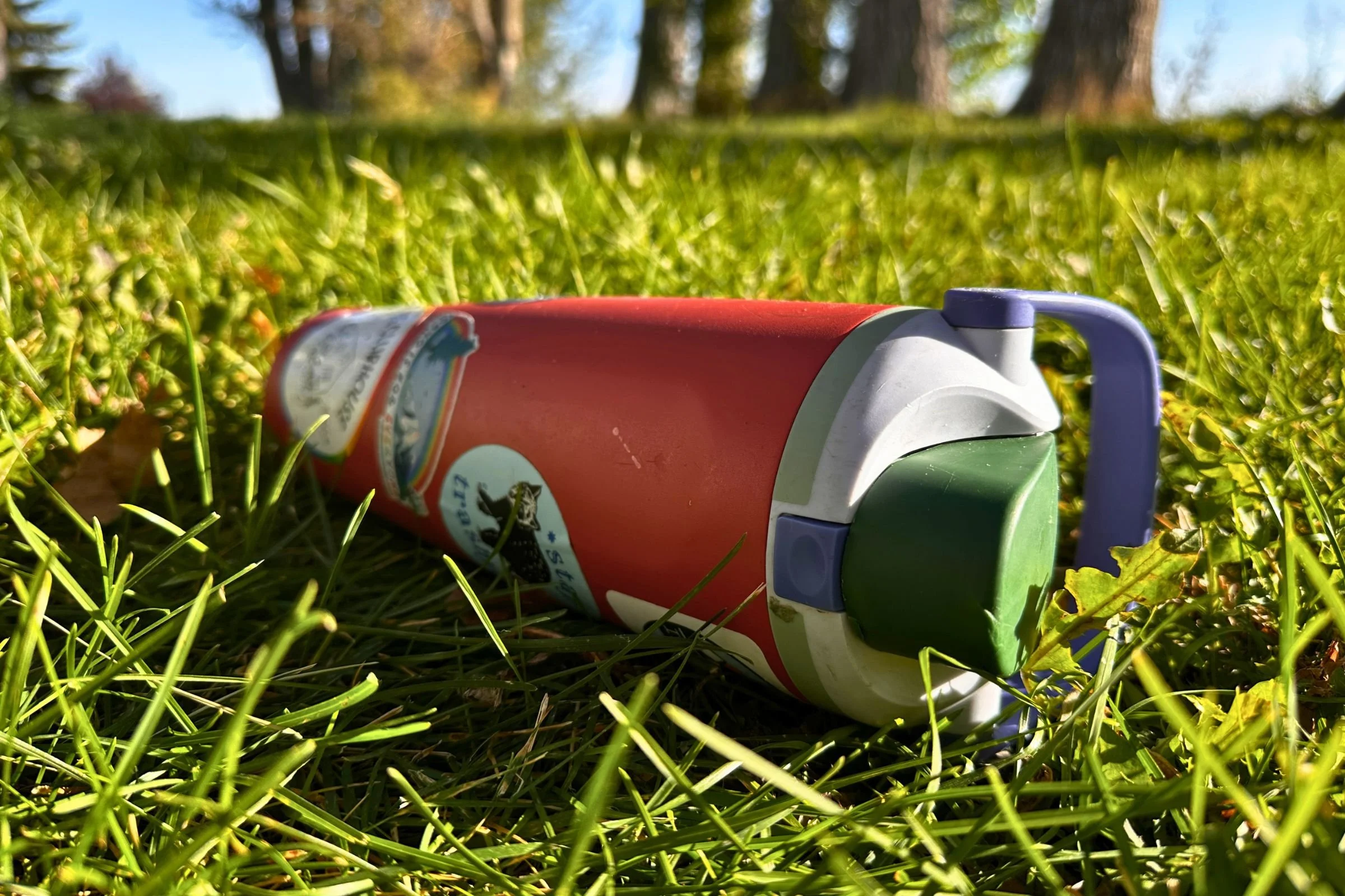The Owala Free Sip Sway 40 oz laying on its side in the grass.
