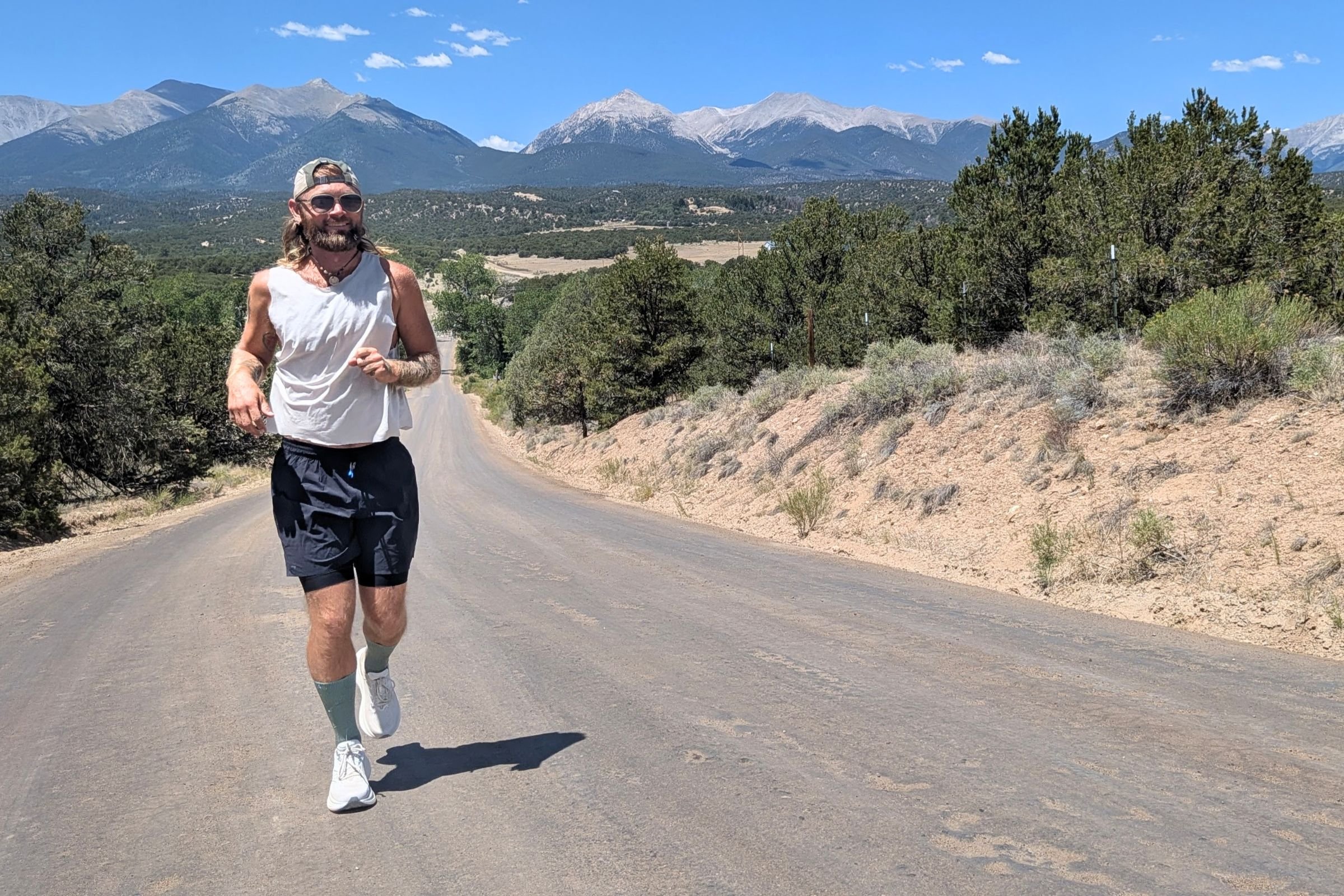 A man running on a road with mountains in the background, wearing the Saucony Triumph 24 Road Running Shoe.