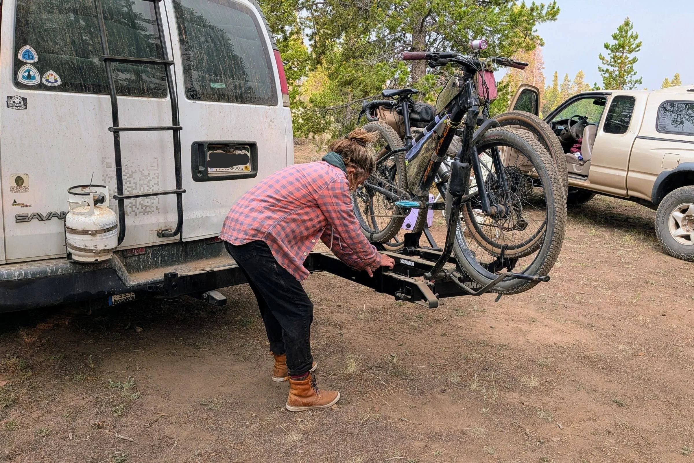 A woman loads a bicycle onto a Yakima EXO Swing mounted on a trailer.