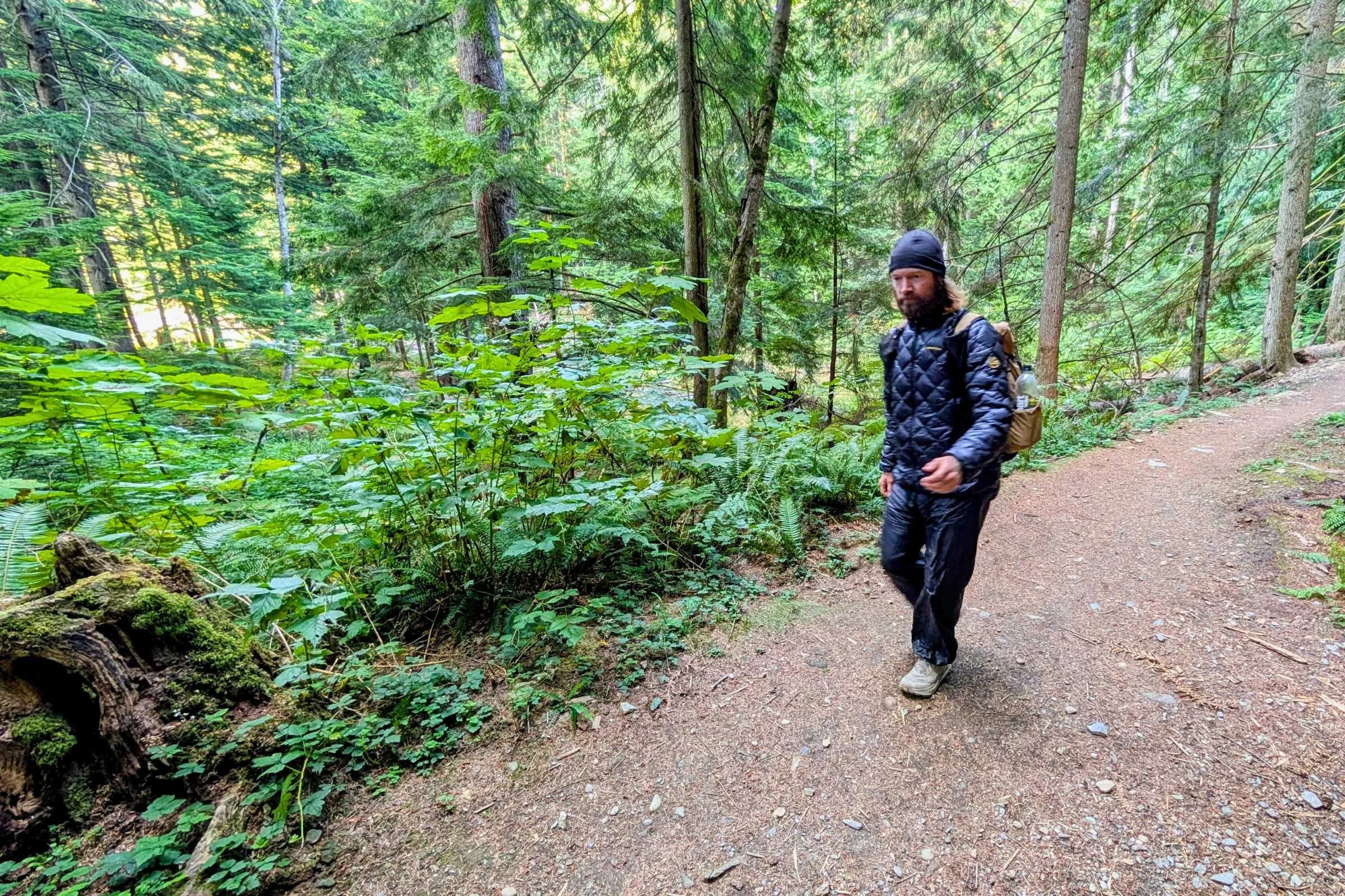 Hiker walking wooded trail in La Sportiva Lumina down jacket