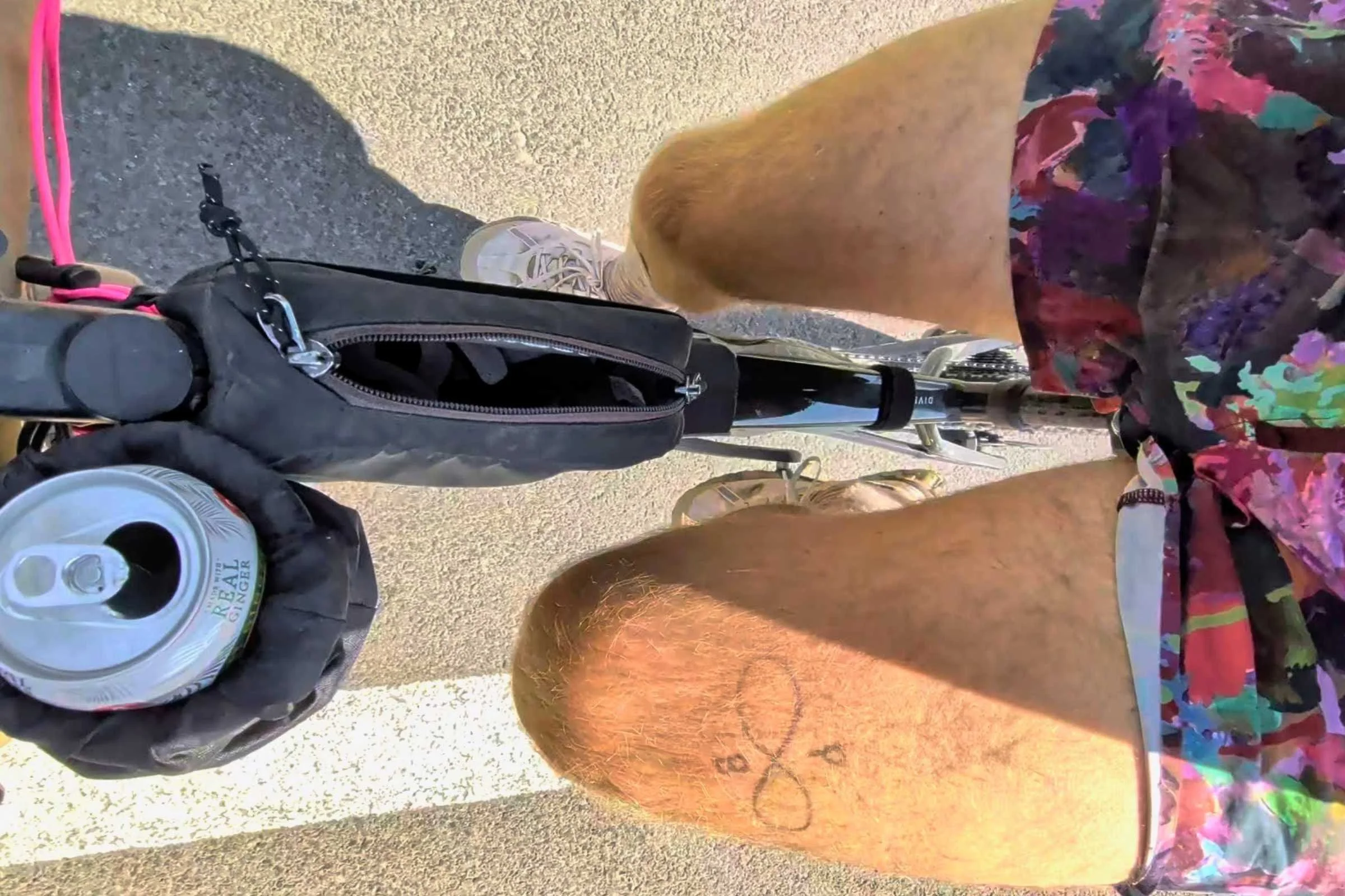 A man rides a bicycle with can holder wearing Janji AFO Middle Running Shorts