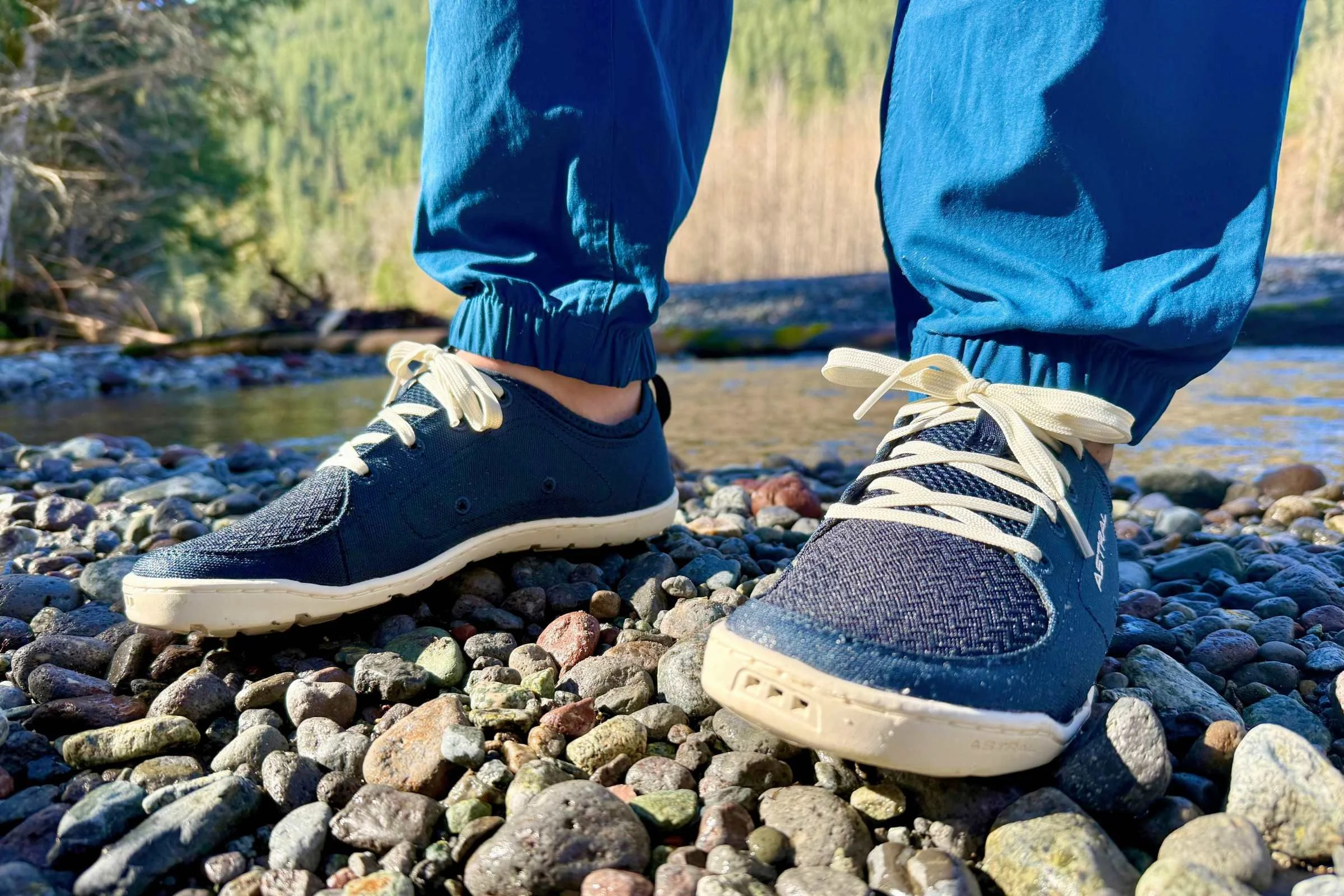 Person wearing the Astral Loyak on the pebbly shore of a river