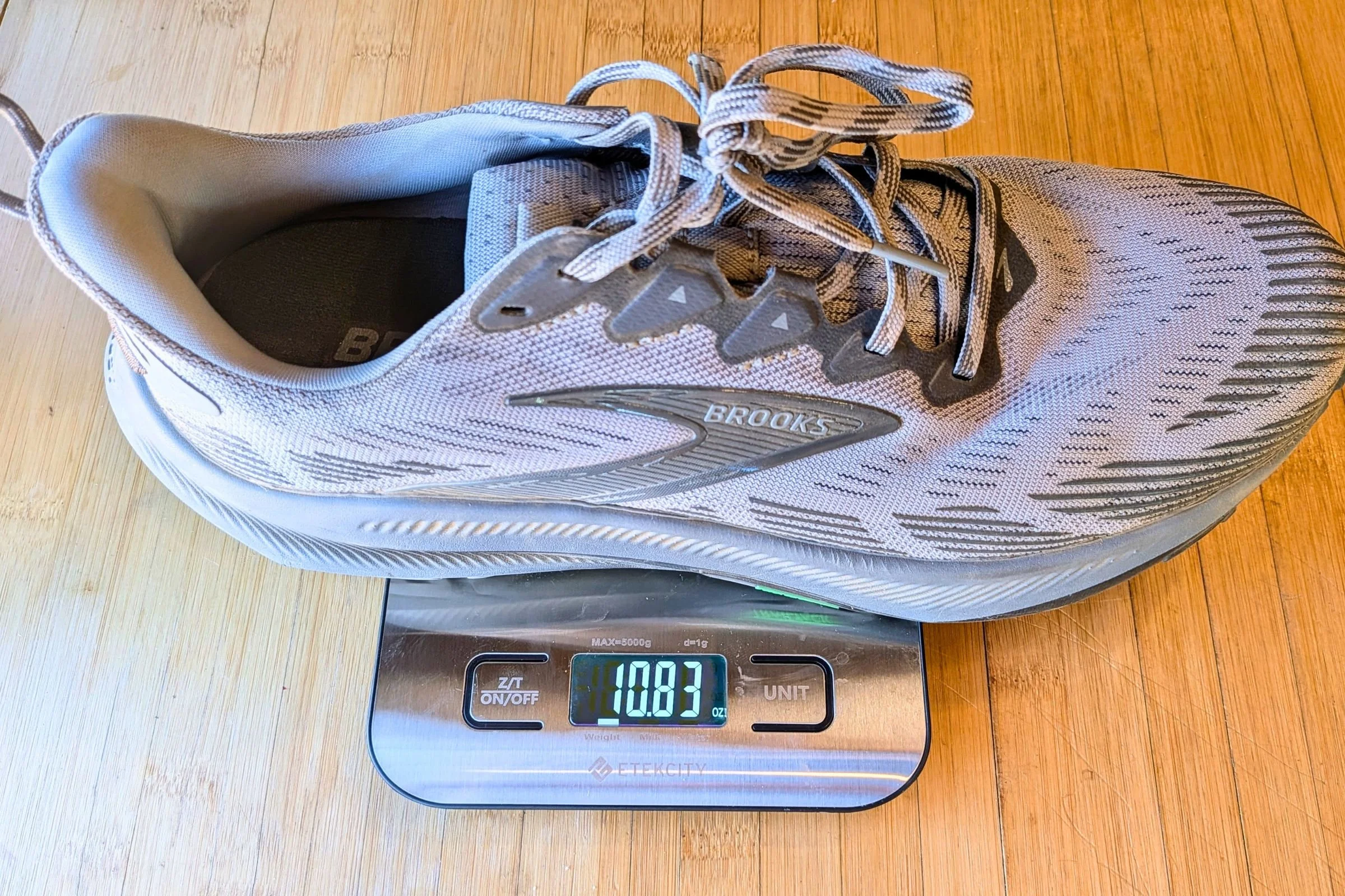 Brooks Ghost trail running shoe on a scale showing 10.83 oz.