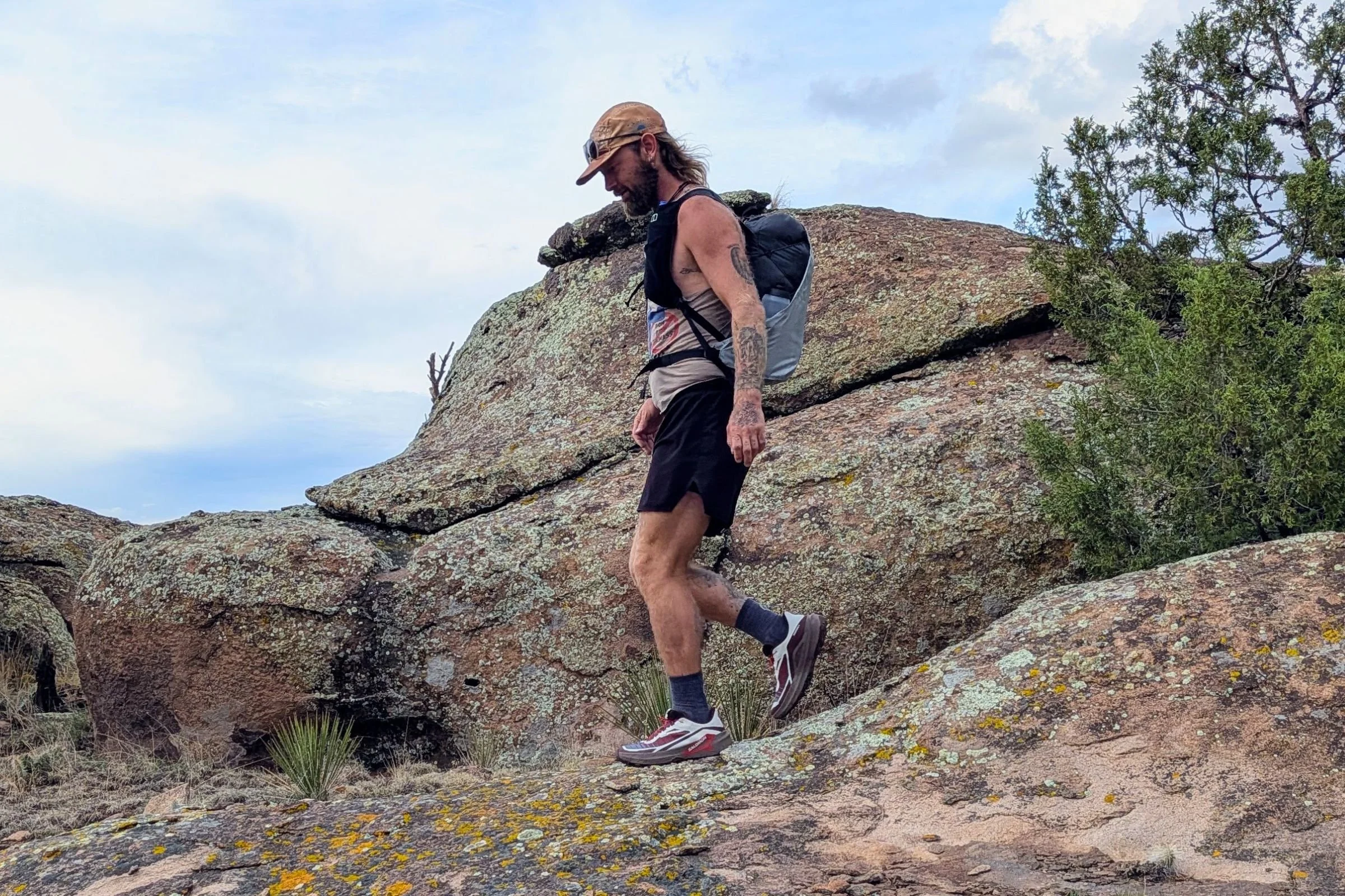 Man wearing Salomon Genesis 2 shoes, walking on rocky terrain.