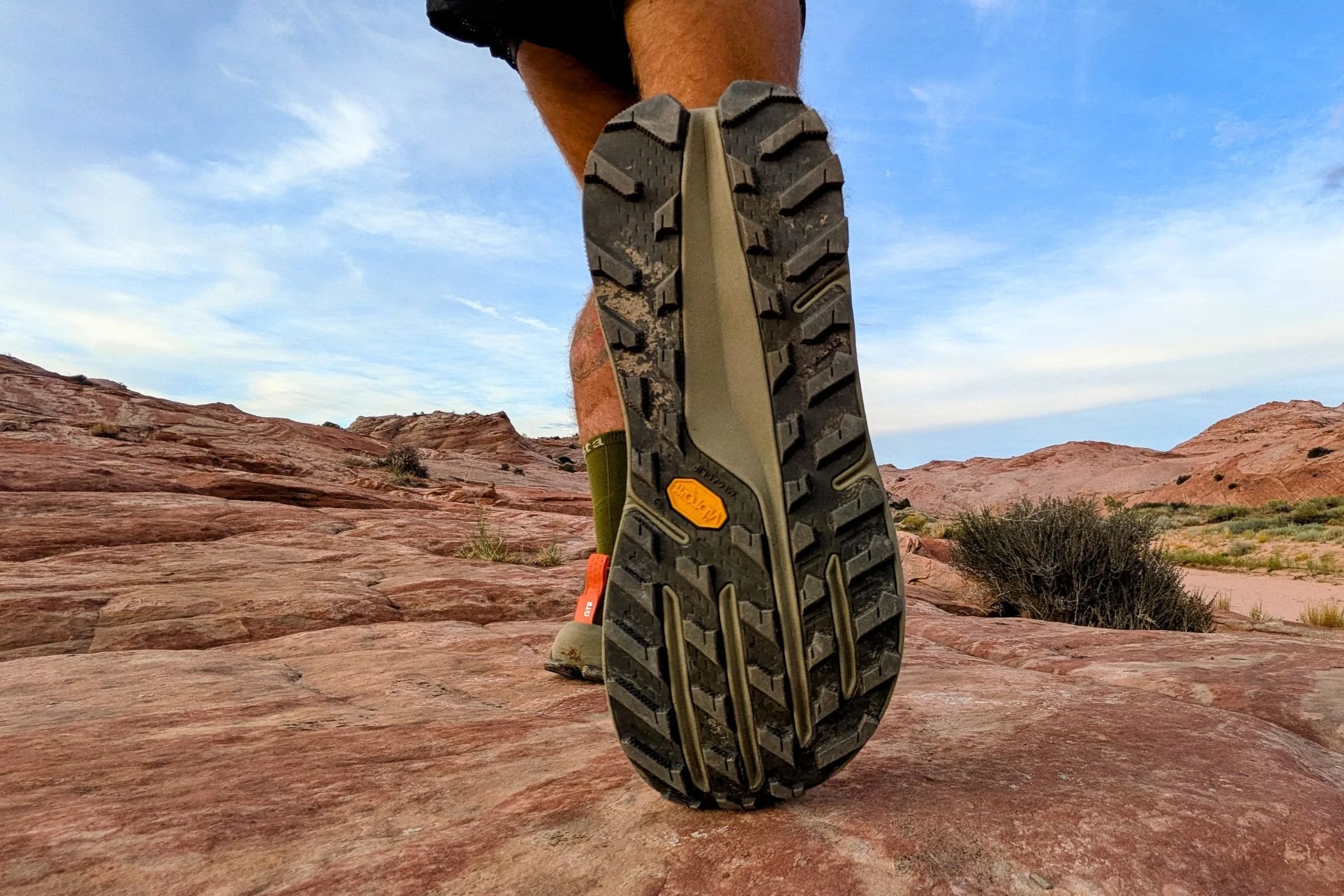 A person wearing the Altra Olympus 7 stands on a rocky trail.