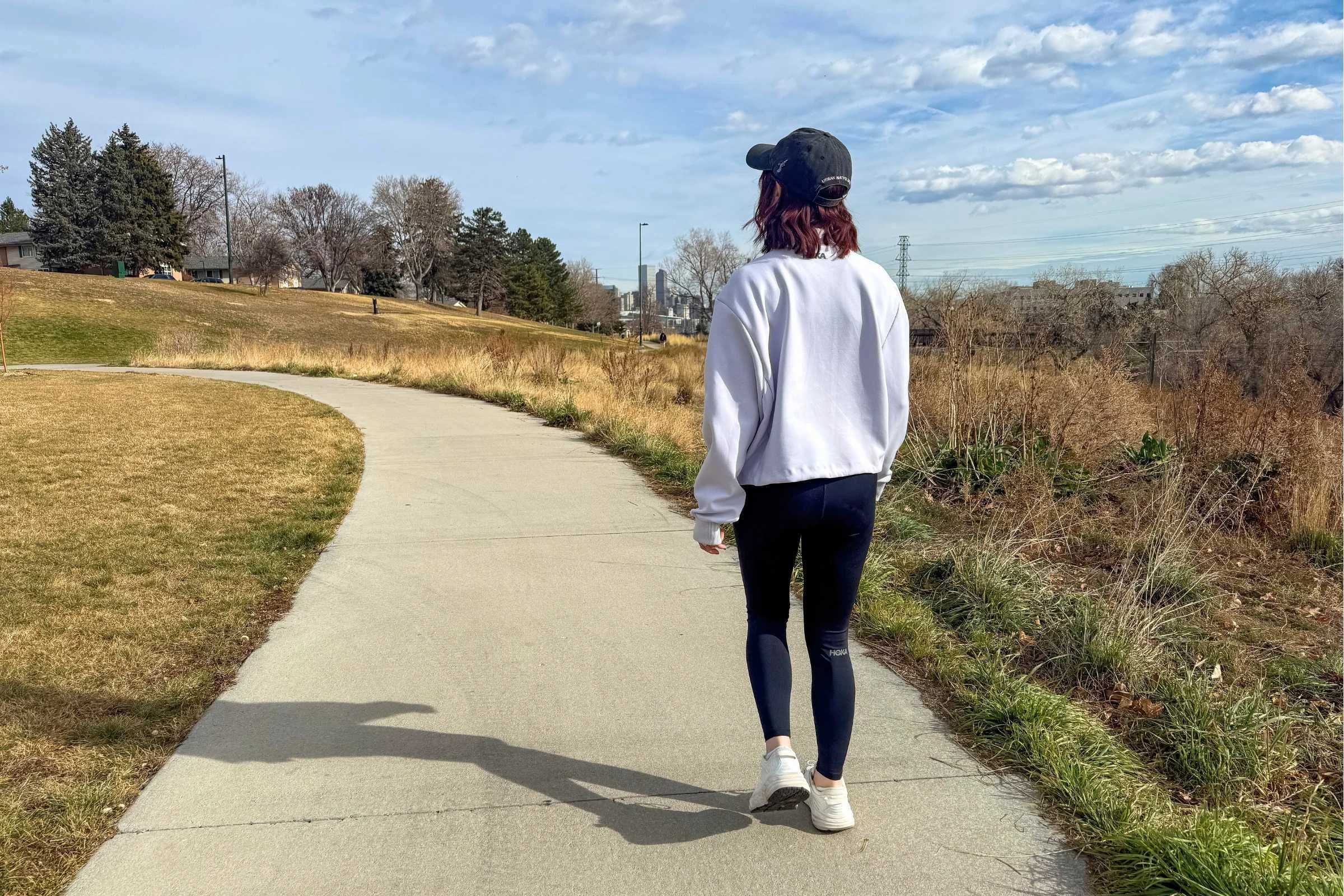woman walks on bike path in white hoka bondi sr shoes