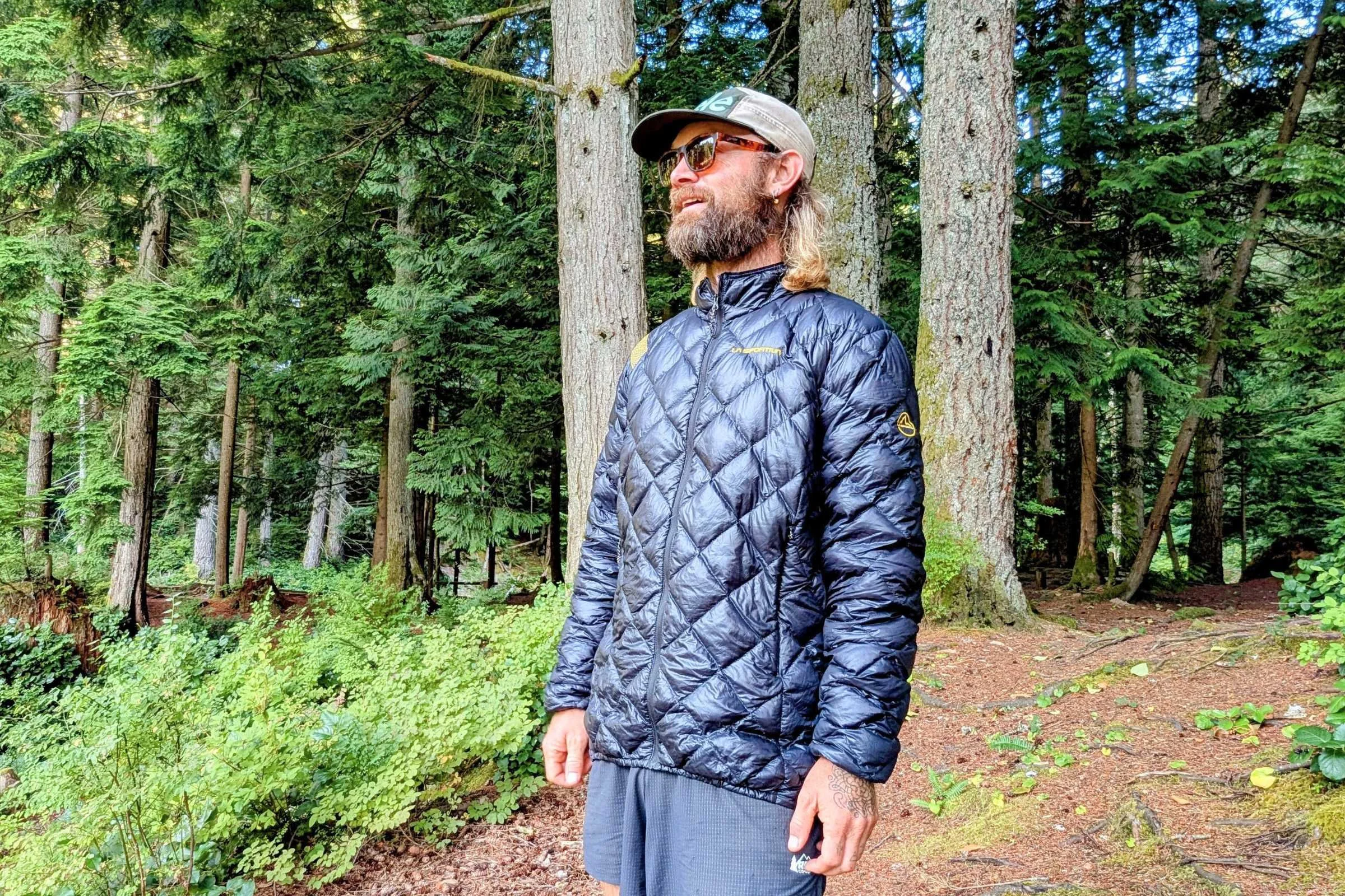 Man standing in forest wearing La Sportiva Lumina down jacket
