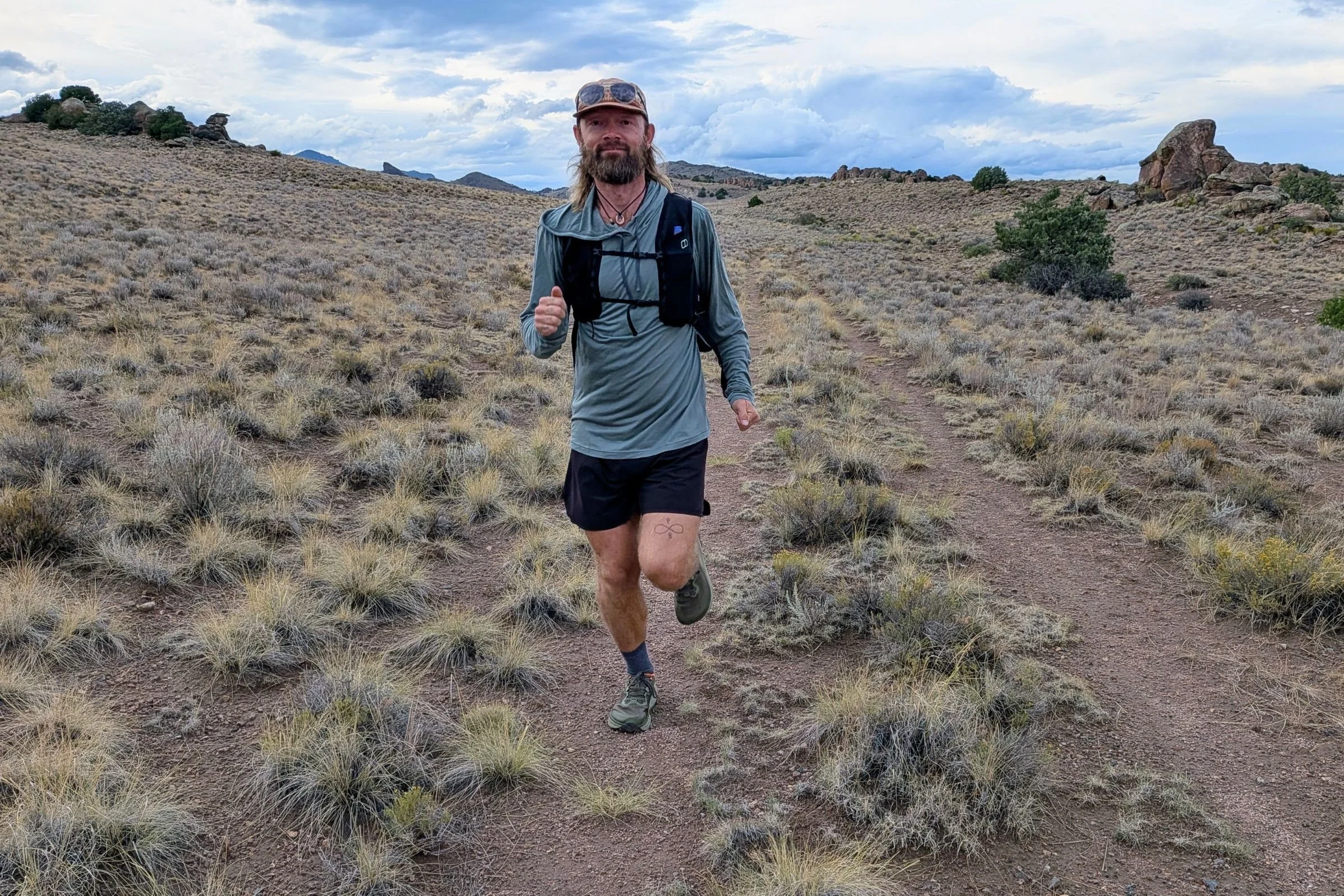 A man wearing the Altra Olympus 7 runs along a desert trail.