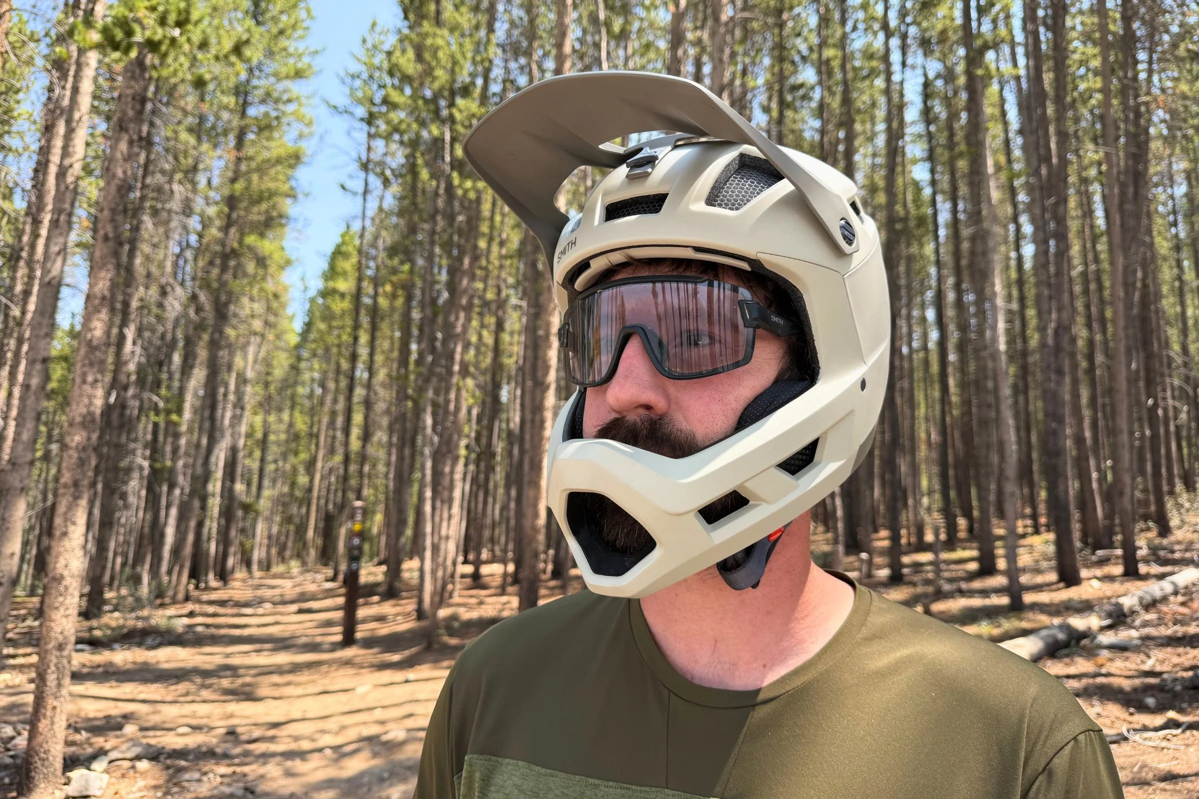 A person wearing Smith Mainline Mips and sunglasses stands among trees in the woods.