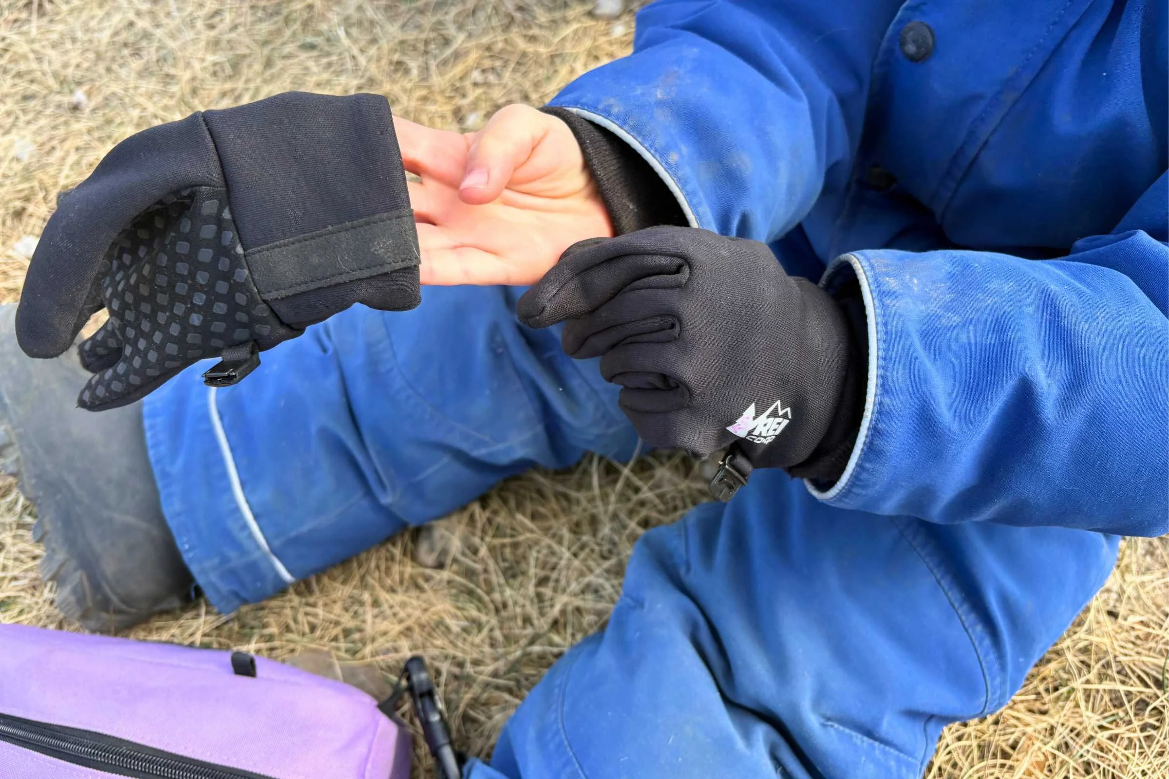 Child pulling on black REI Co-op Flash gloves