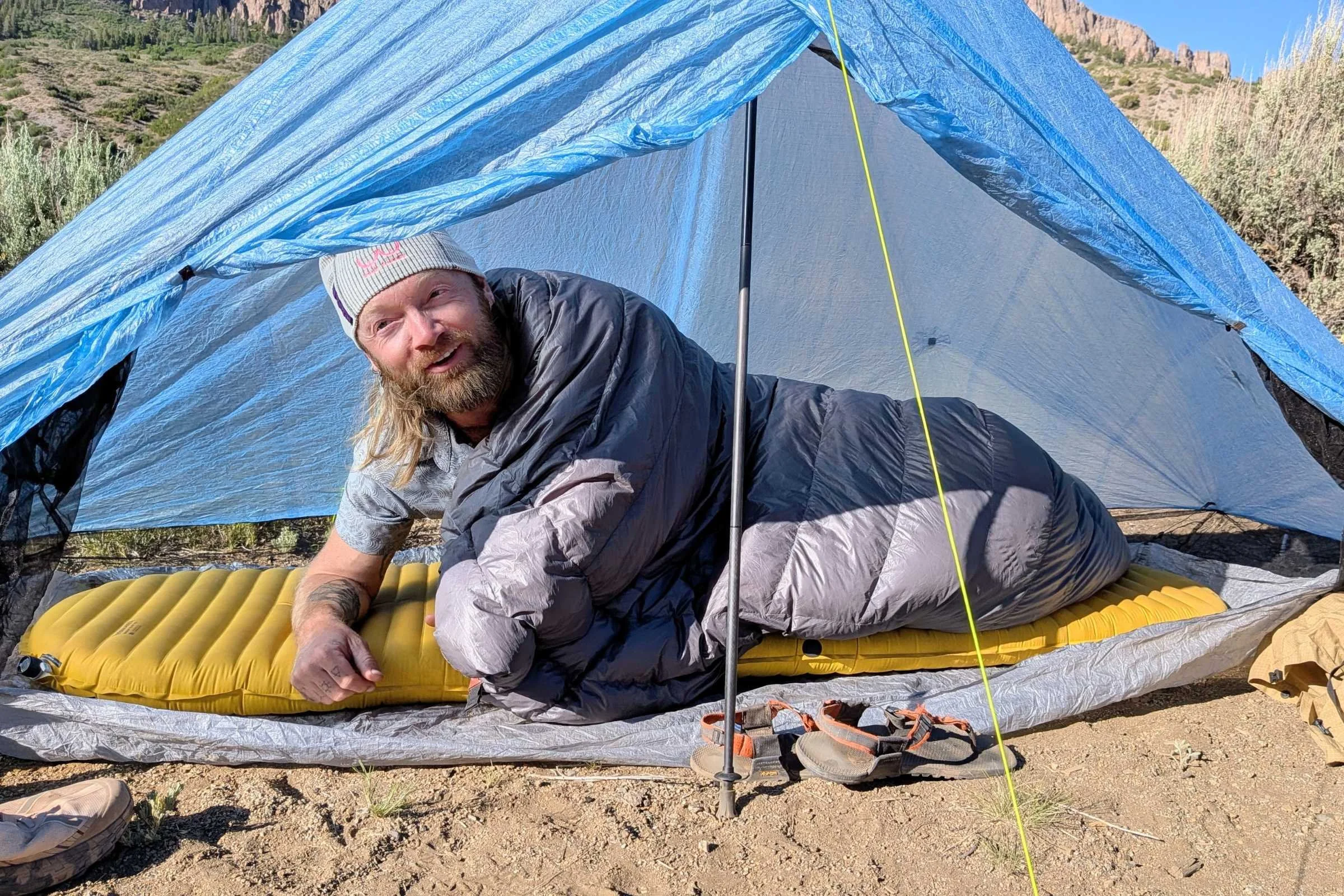 Man sitting inside a Zpacks Hexamid Ultralight Tent with a sleeping bag.