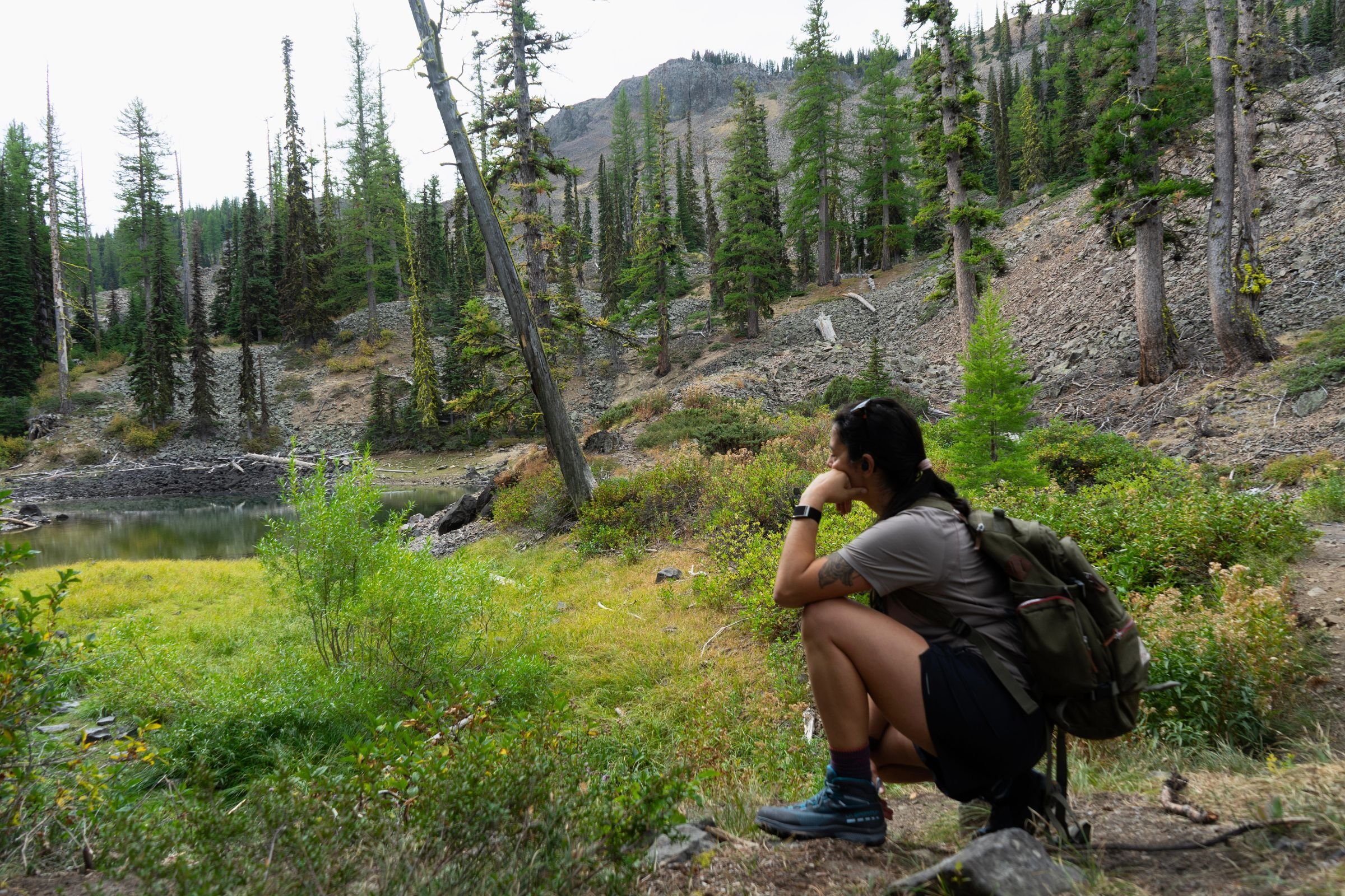 Hiker squatting and enjoying the scenery while hiking in the La Sportiva TX Hike Mid GTX boots