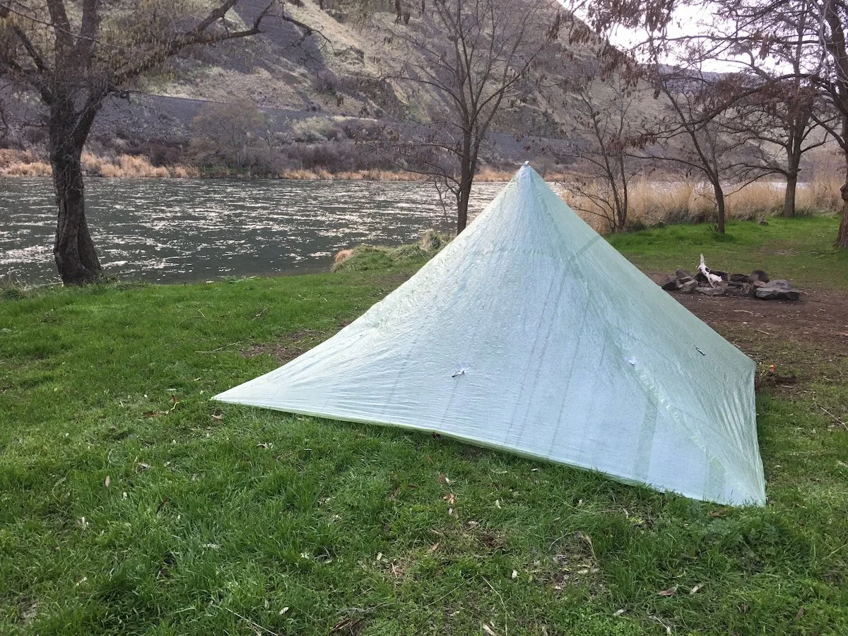 The Mountain Laurel Designs Duo Mid tent on a patch of grass next to the Deschutes River with a fire ring in the background