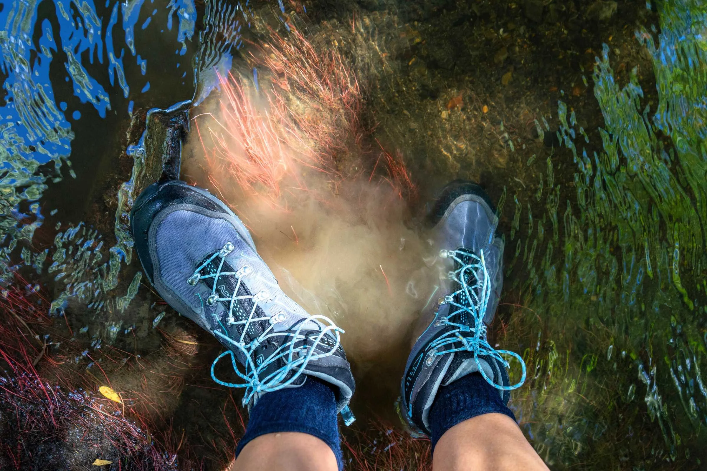 Hiker navigating muddy, wet trail conditions in waterproof boots