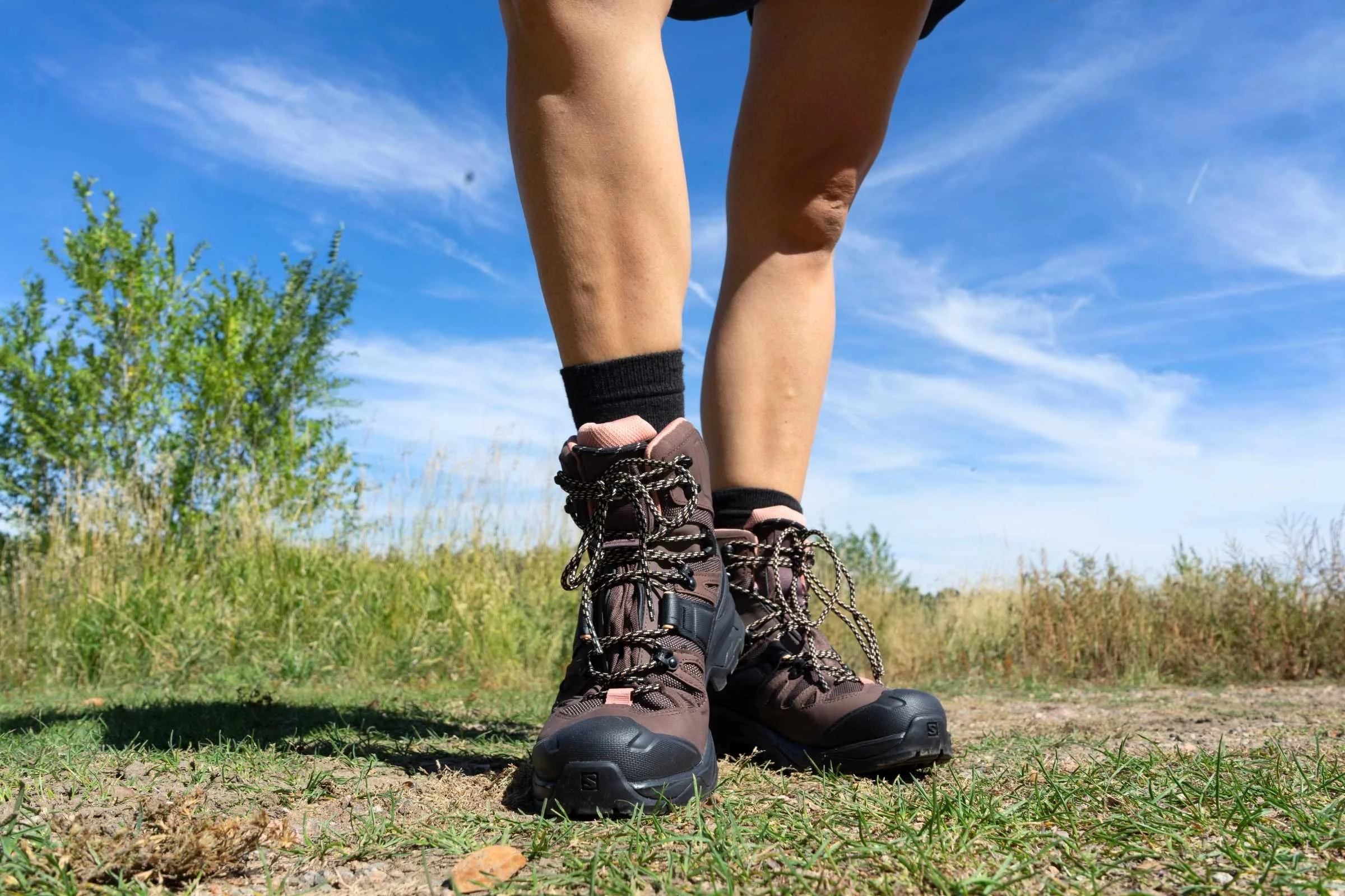 front view of the salomon quest 4 hiking boots on a grassy trail