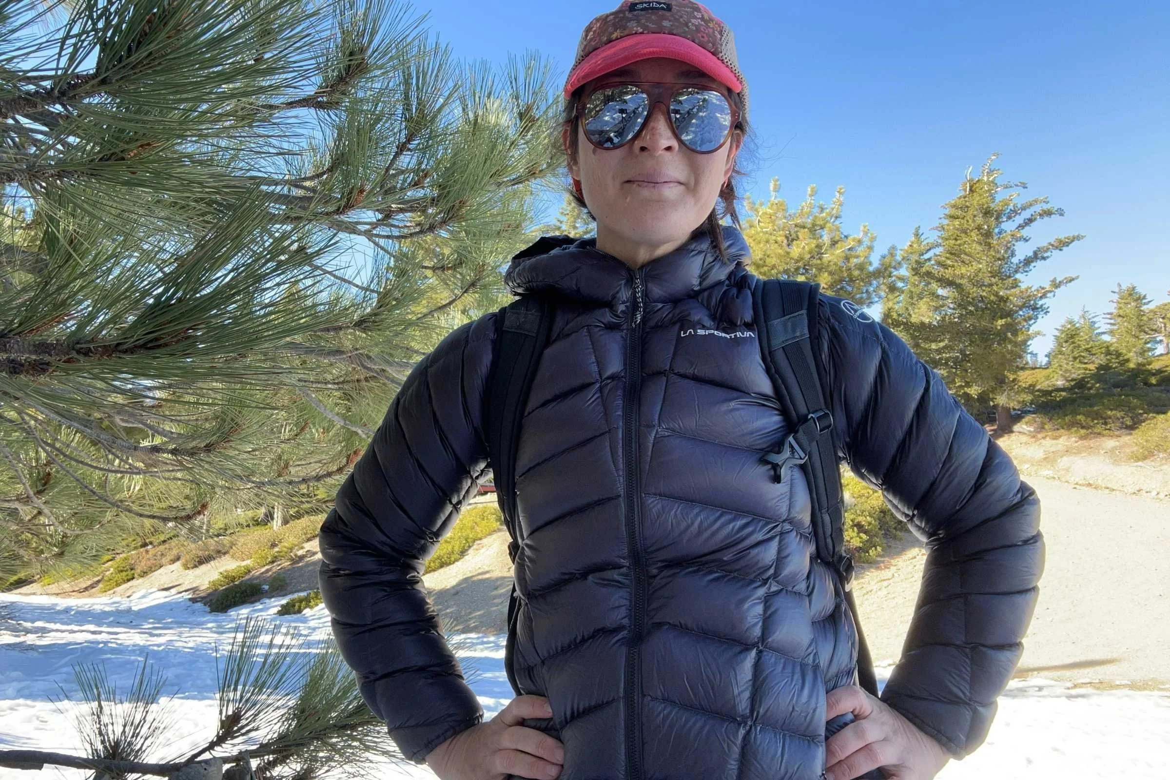 Woman wearing La Sportiva Lumina down jacket on snowy forest trail