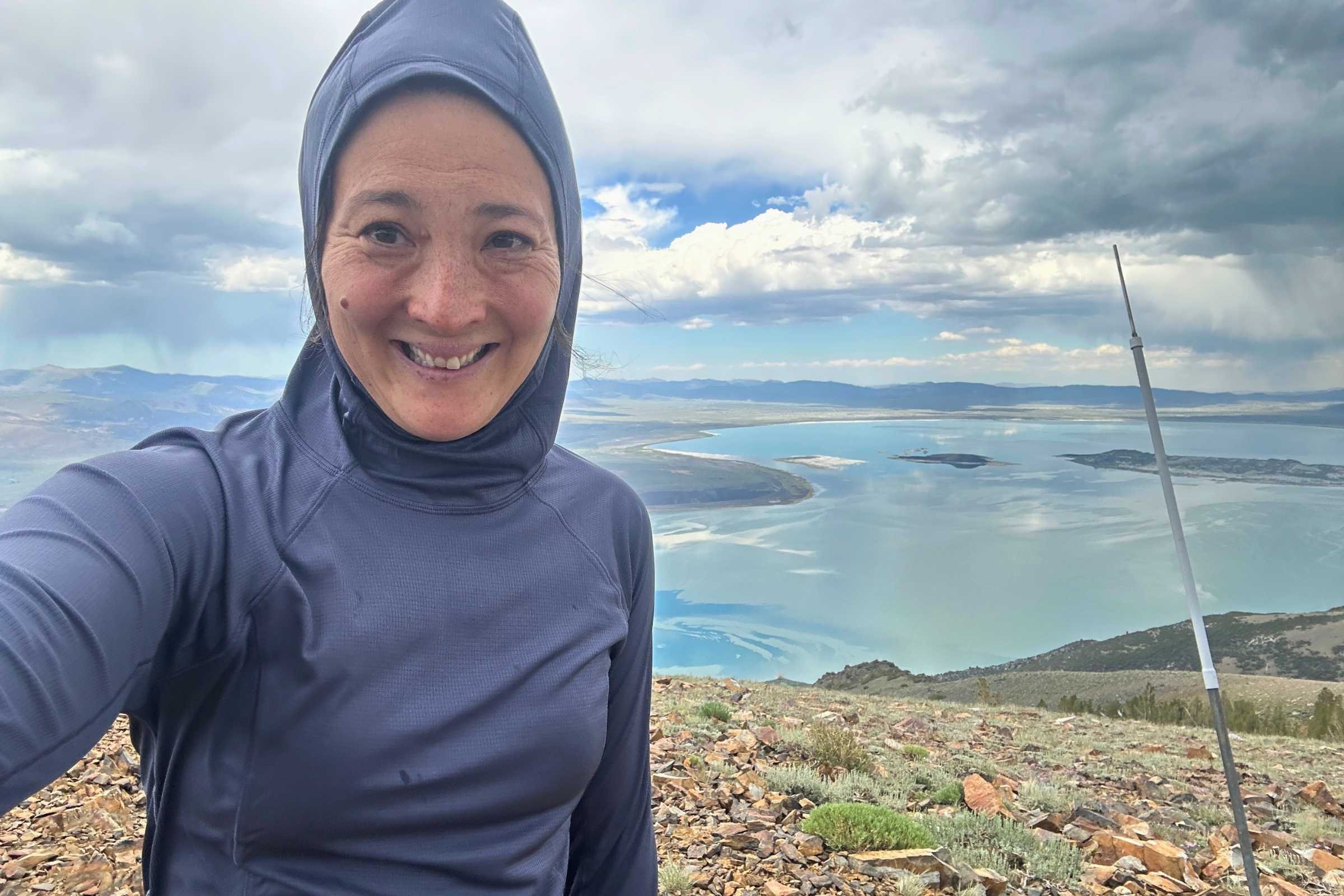 Liz Thomas wearing the REI Flash Shade Hoodie while hiking with the hood up