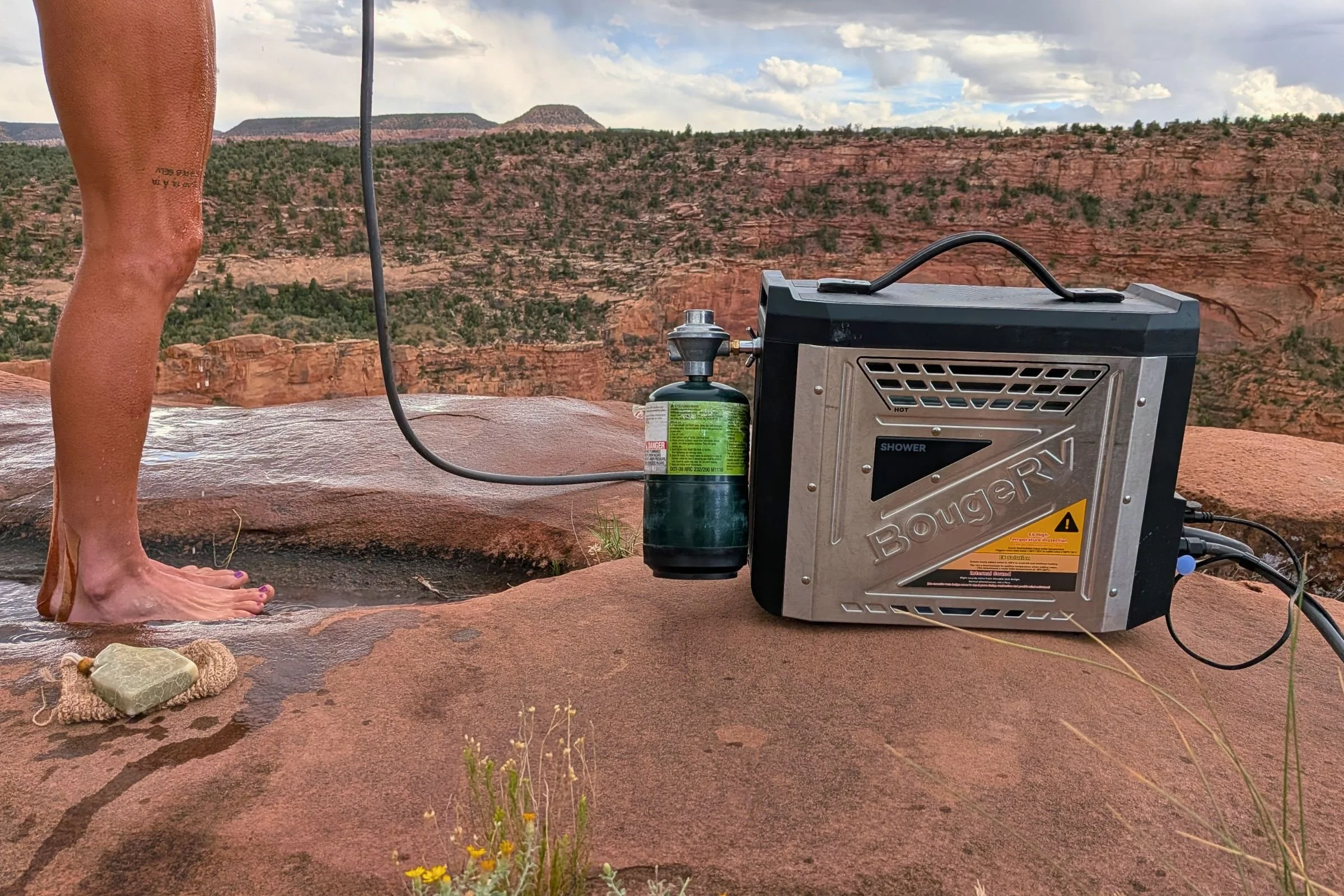 BougeRV Portable Propane Outdoor Water Heater outdoors beside a person standing on a rock.