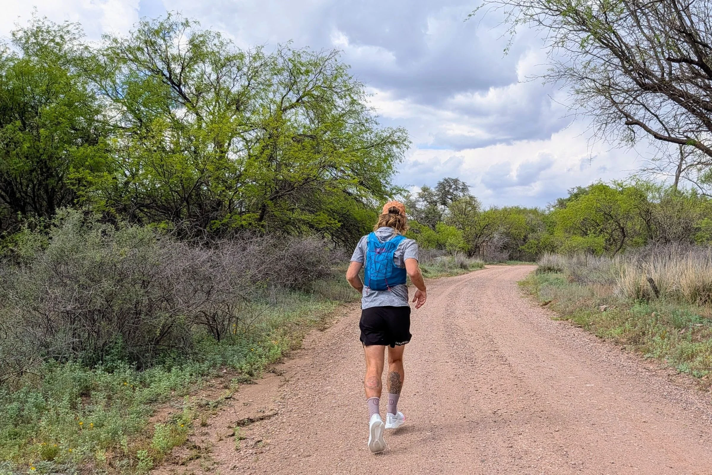 Man running across outdoor terrain while wearing a Nathan VaporAir pack.
