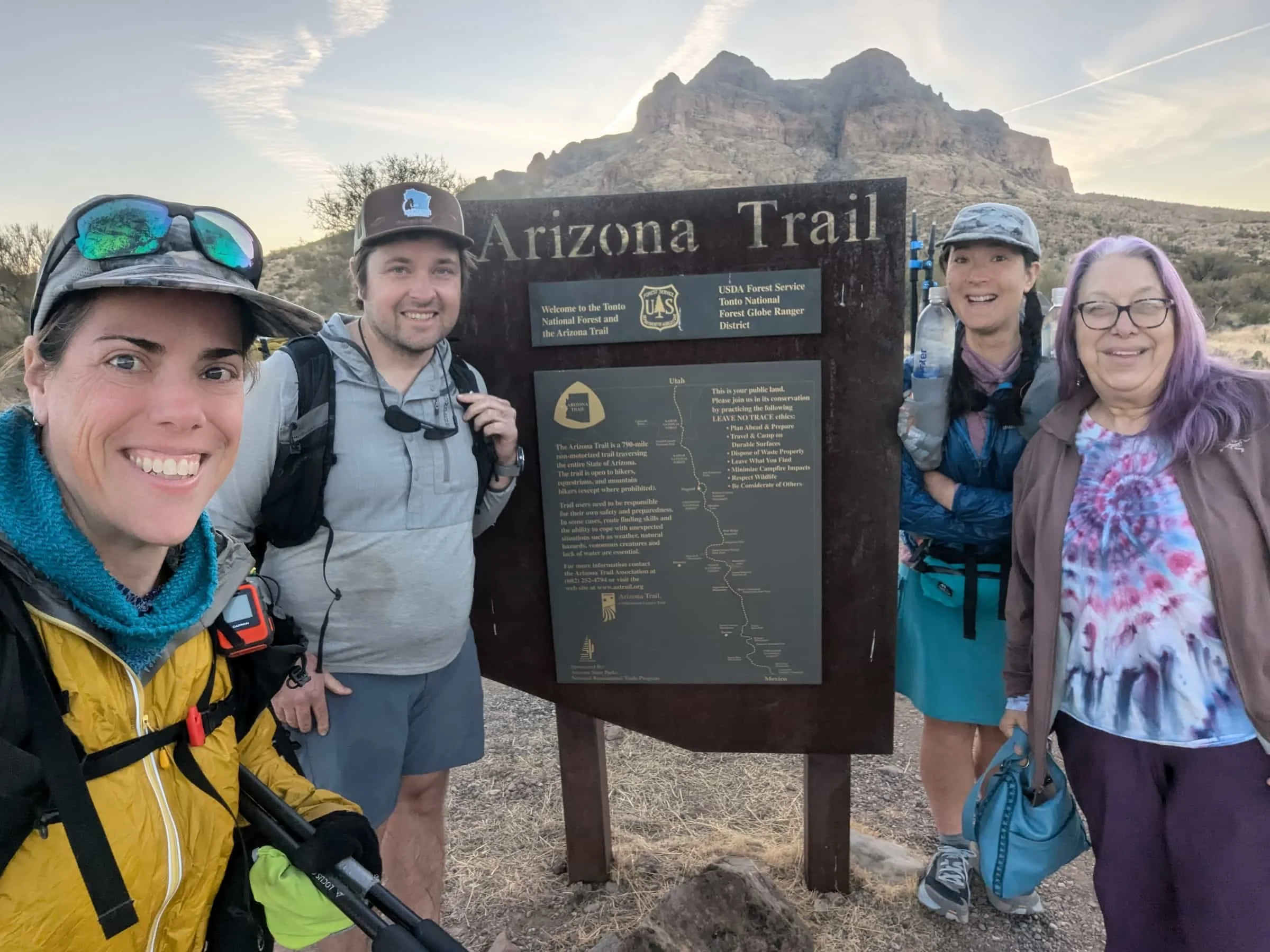 3 hikers and a trail angel at a trailhead sign on the arizona trail