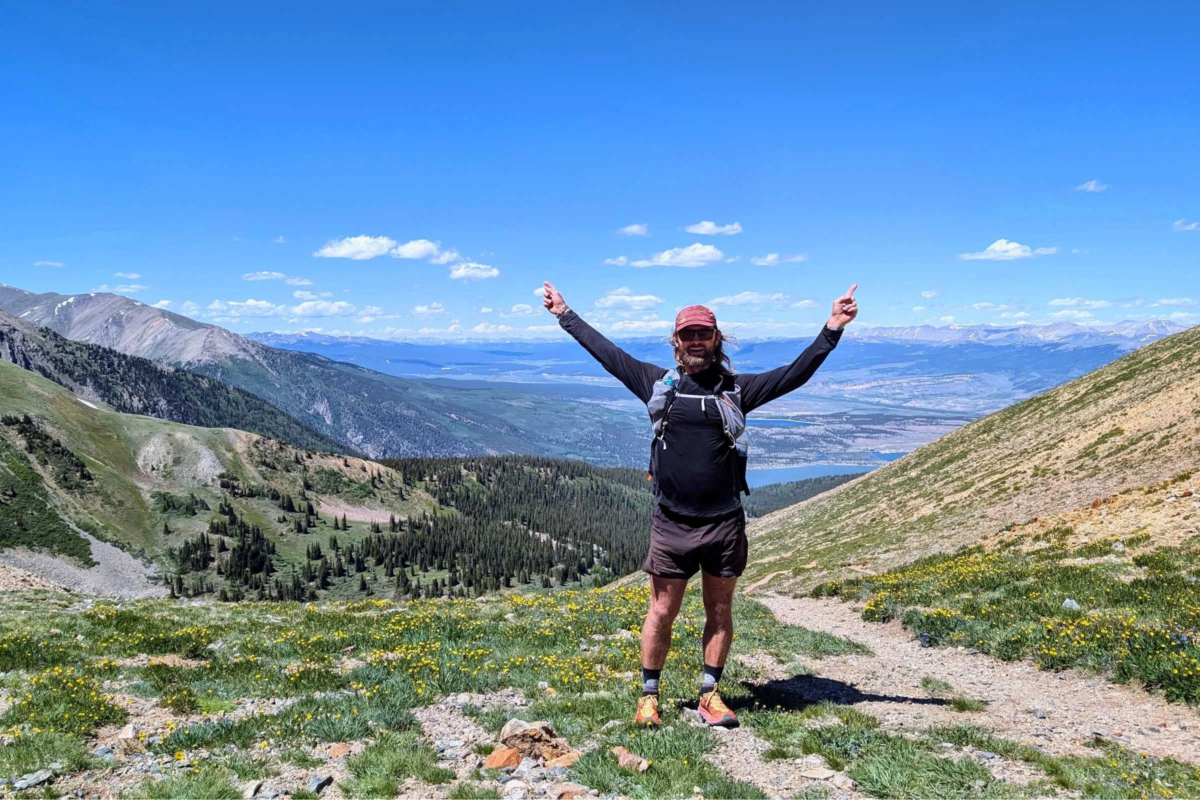 Man posing on a trail wearing the Hoka Speedgoat 6