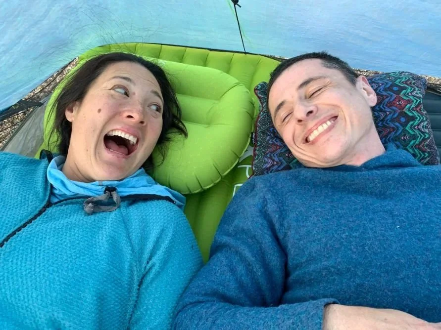 Two people testing two different backpacking pillows in a tent