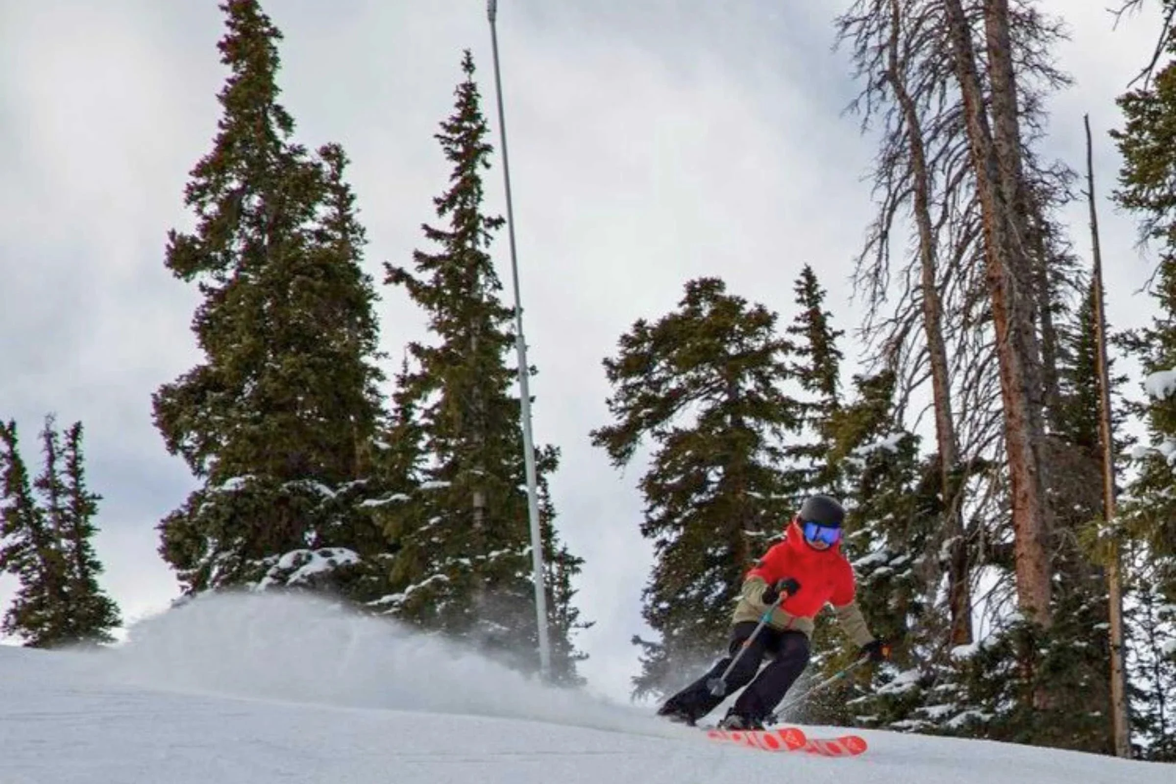 Skier wearing black snow pants and red ski jacket