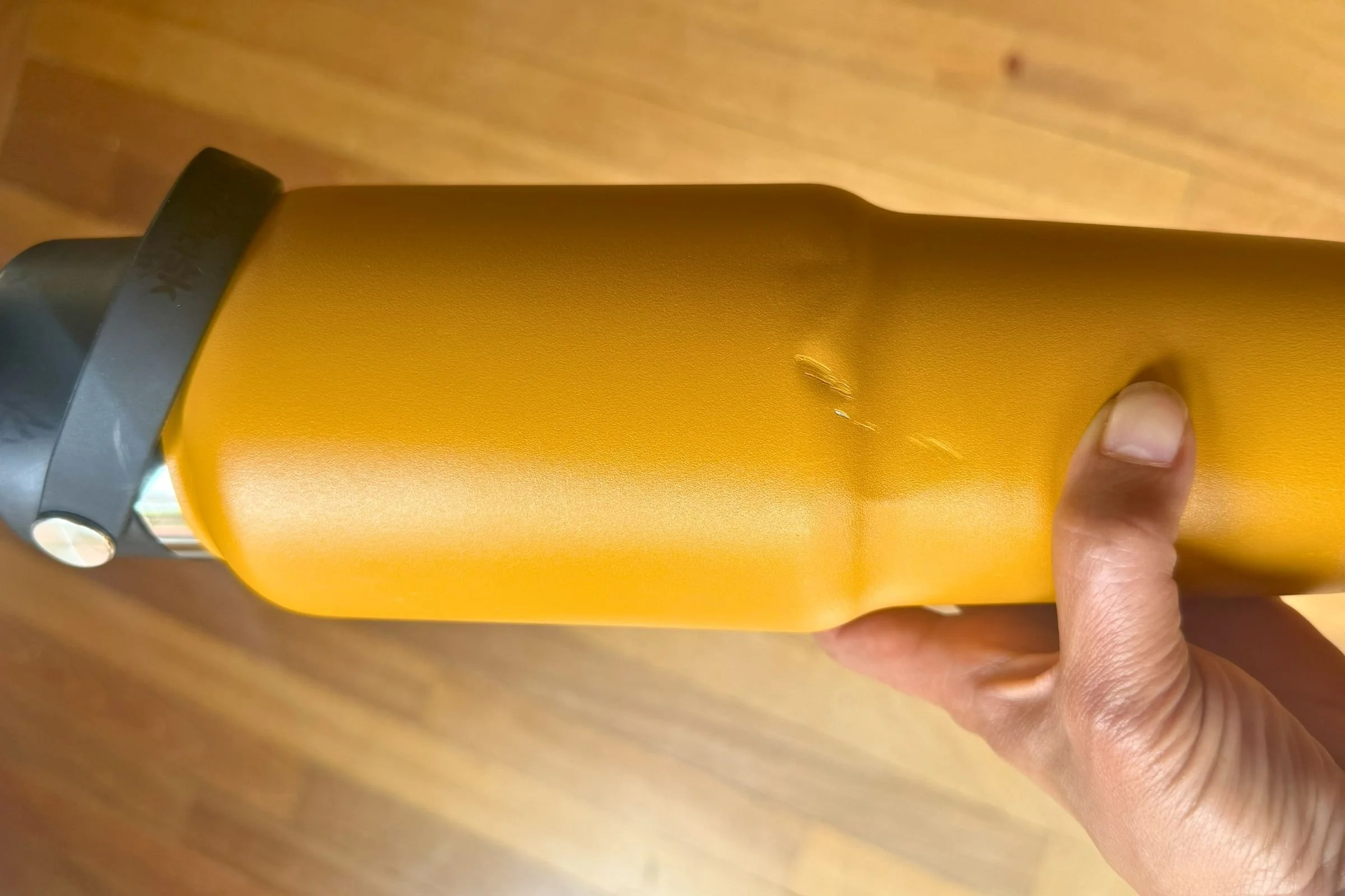 Person holding a Hydro Flask 32 oz Travel Bottle with a minor exterior dent after drop testing.