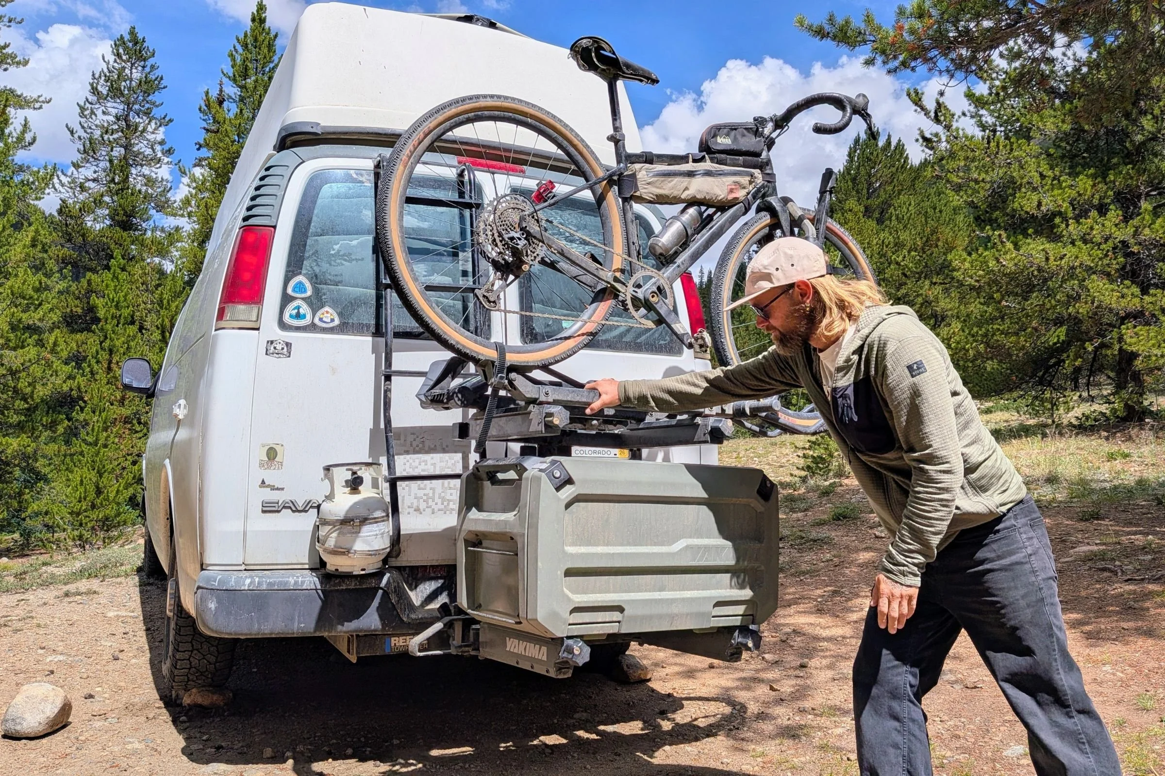 A man loads a bike onto a Yakima EXO DoubleUp 2-Bike Hitch Rack mounted on the back of a van.