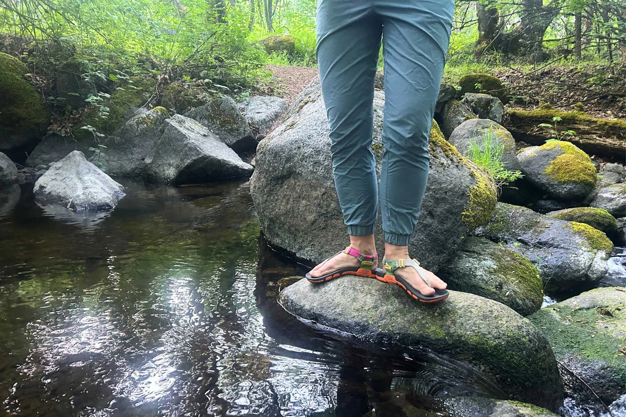 Wearing the Lems Switchback Sandal Knit on a rock next to a stream