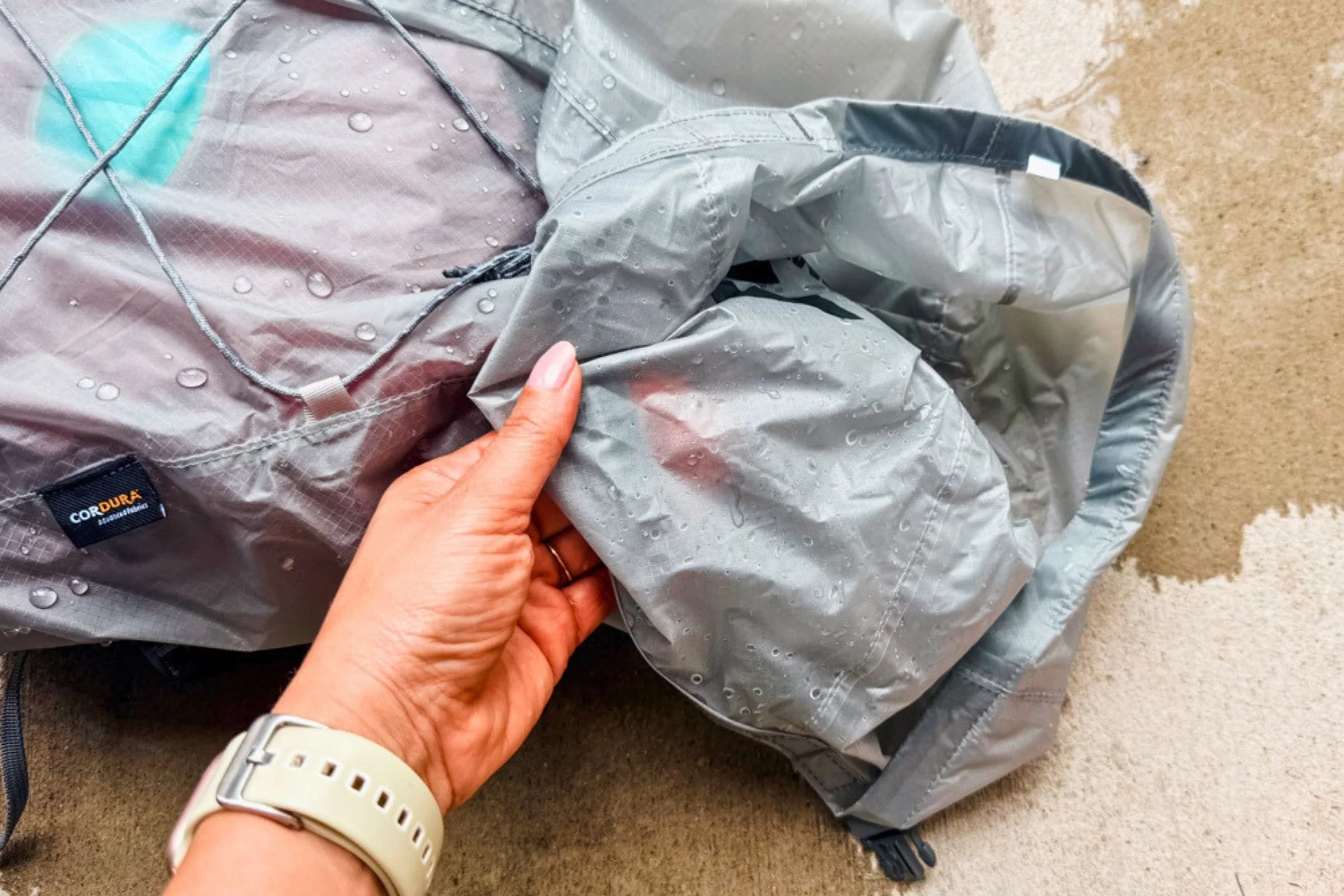 A hand lifts the interior fabric of the Sea to Summit Ultra-Sil Dry Daypack after a water-resistance test