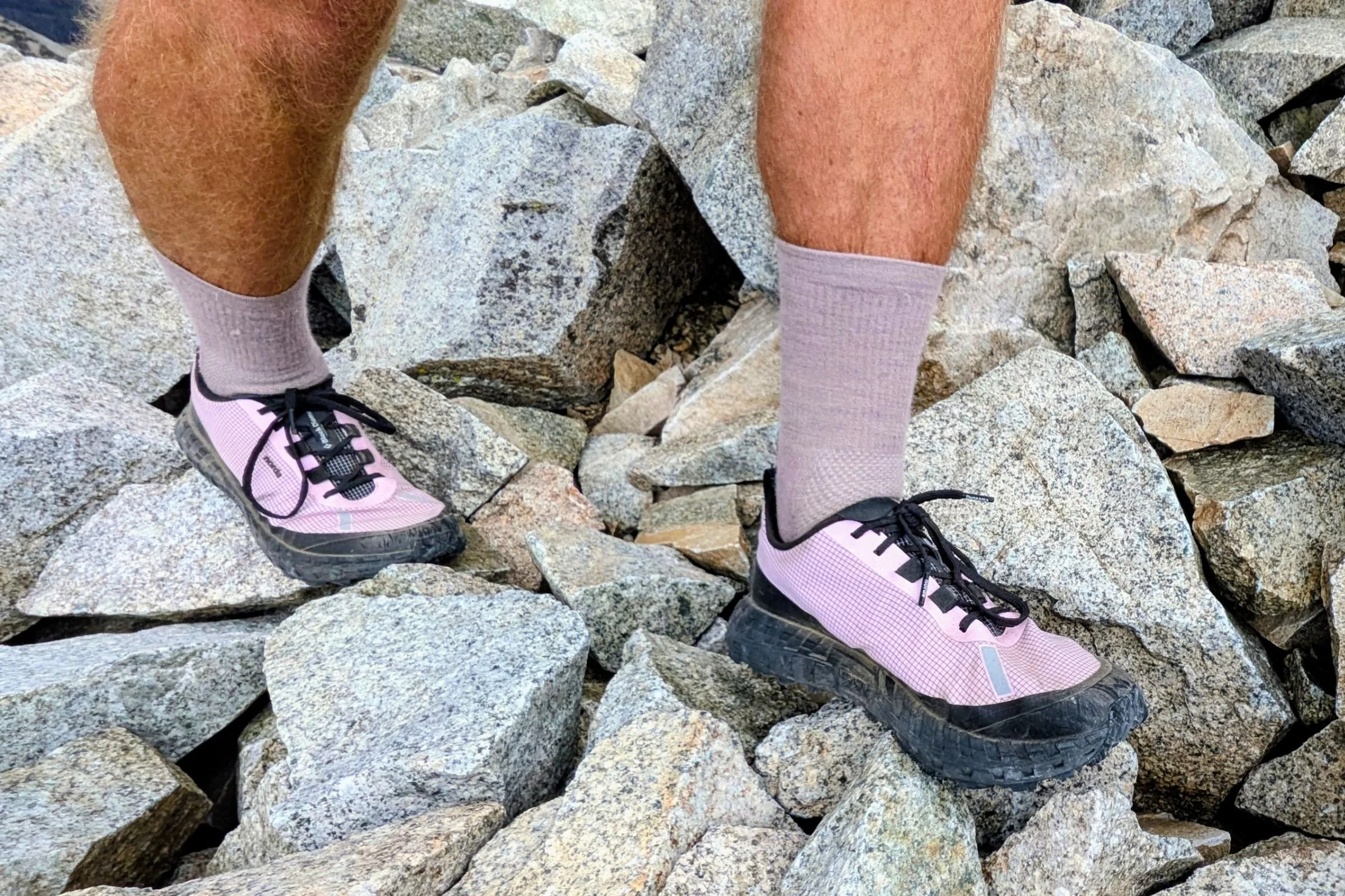 Person wearing pink Norda 000 Trail Running Shoes standing on a rock.