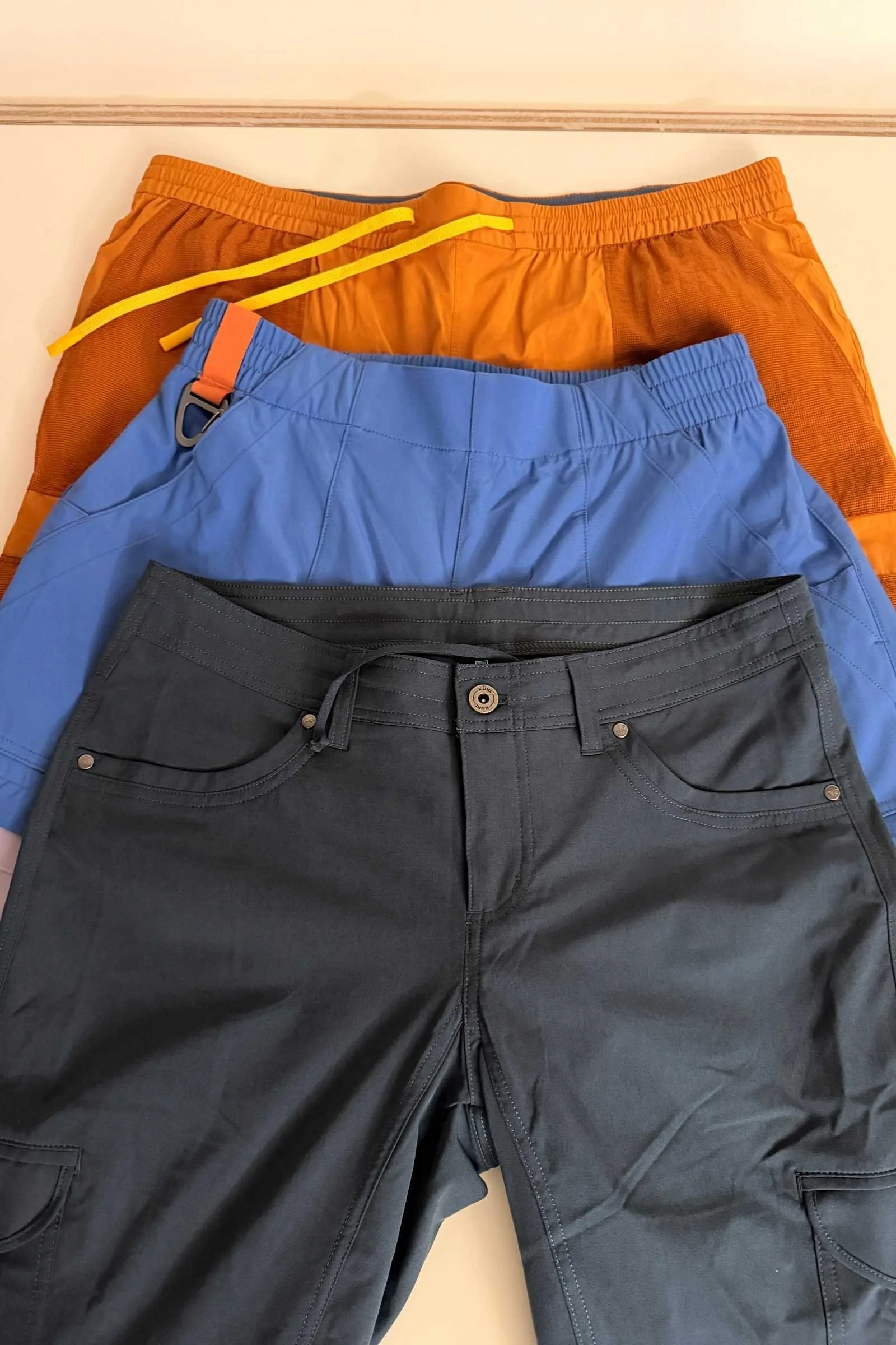 Close-up of three different travel pant waistbands: elastic, zip-fly, and drawstring