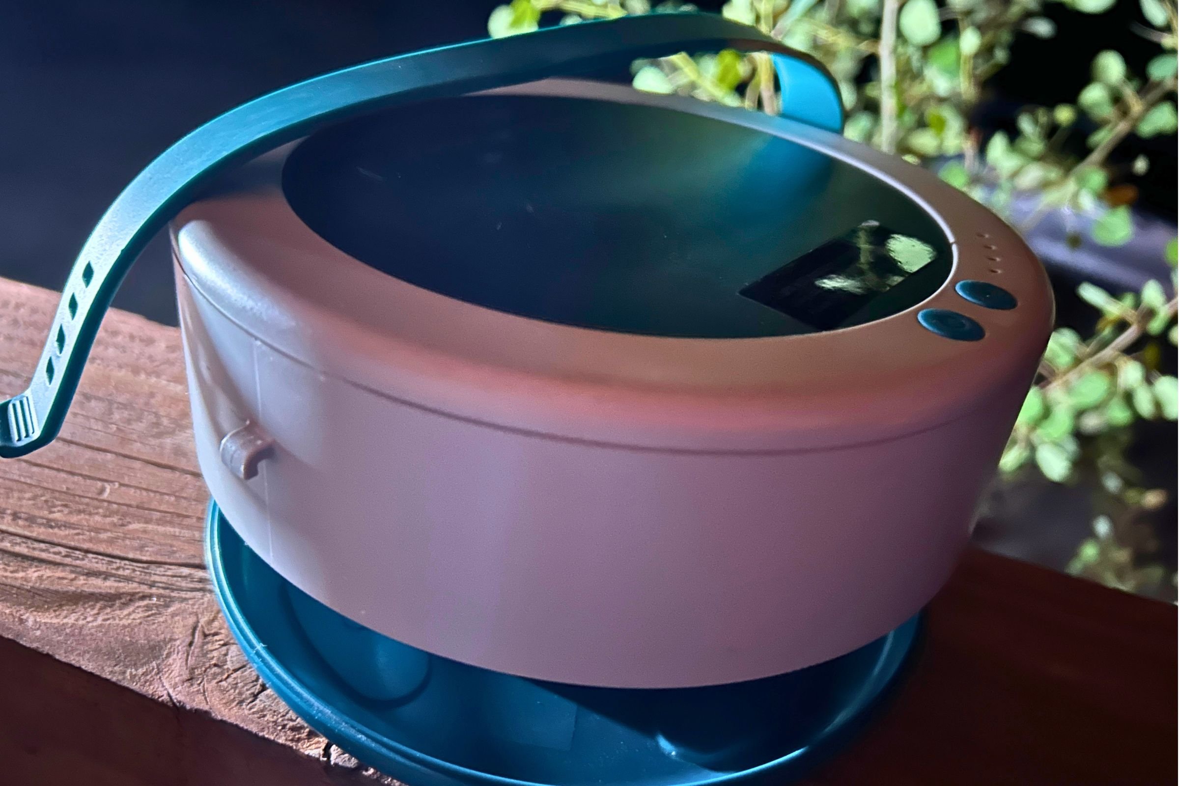 The BioLite Luci Solar String lights have an adjustable hanging strap, visible here as it sits atop the banister on a cabin porch in the Sierra. The area below the hub (between the white and blue parts) is where you store the string.