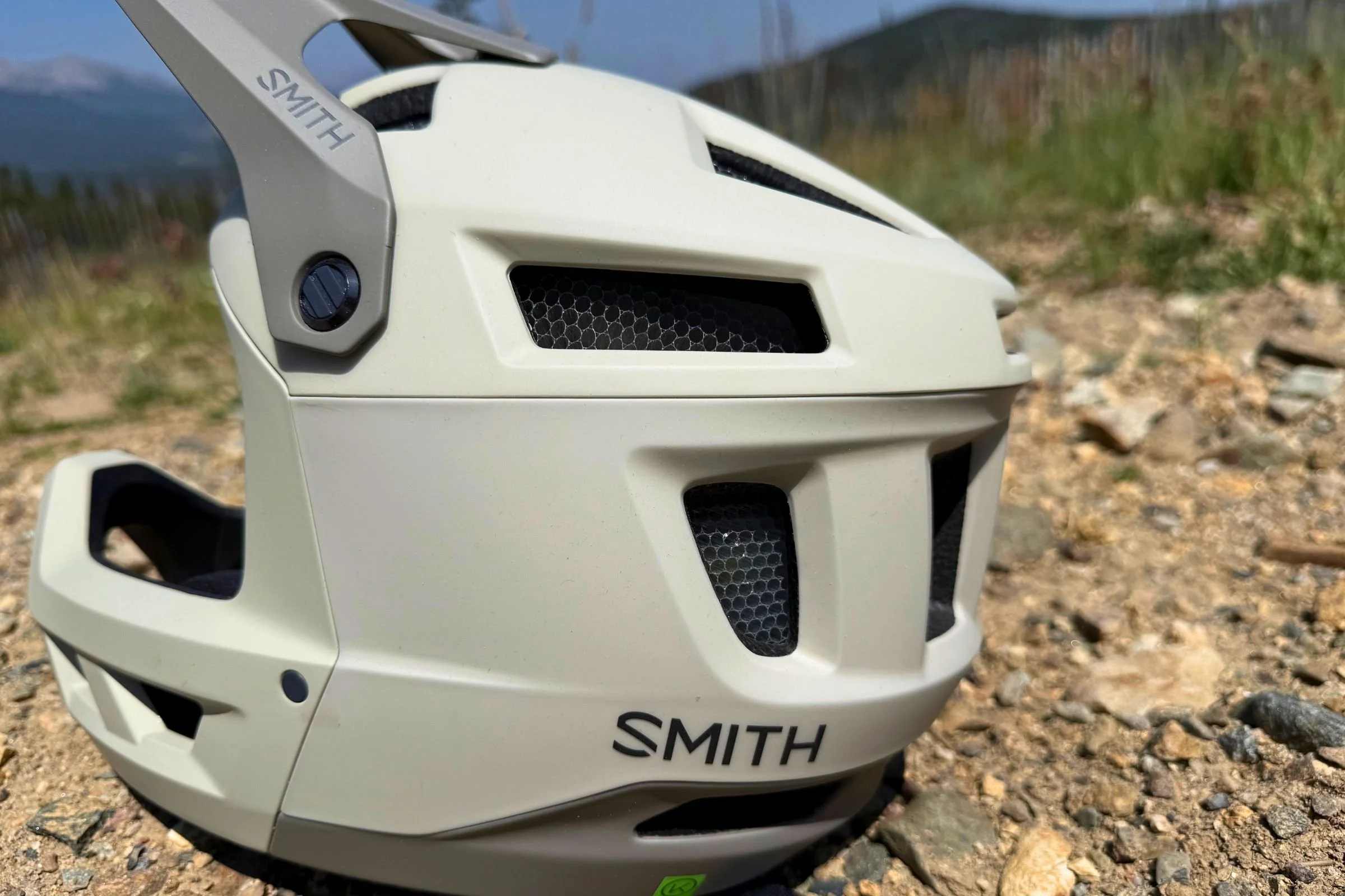 A side view of the Smith Mainline Mips helmet with rocks and grass in the background.