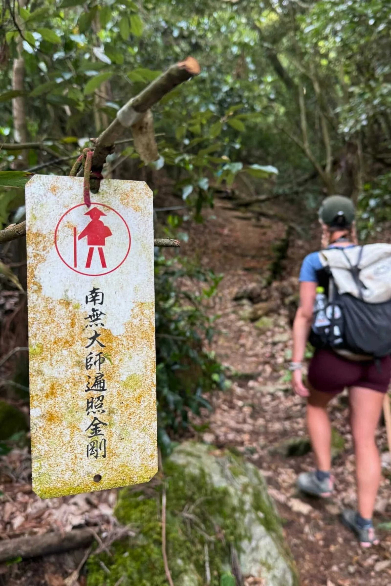 Hiker climbing toward temple 88 with trail marker in the foreground