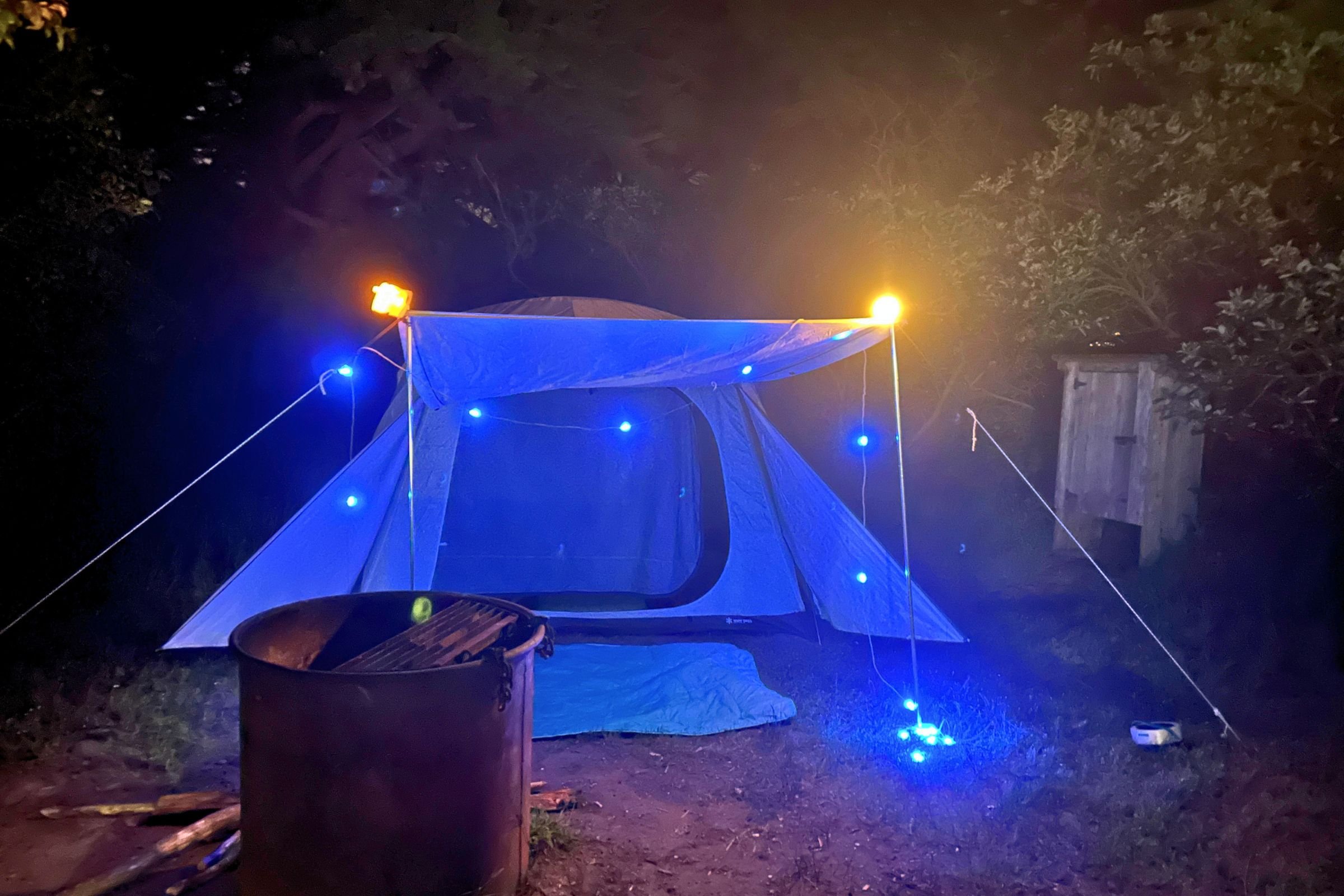 BioLite Luci 44' Solar String Lights cast blue and amber light around a camping tent.