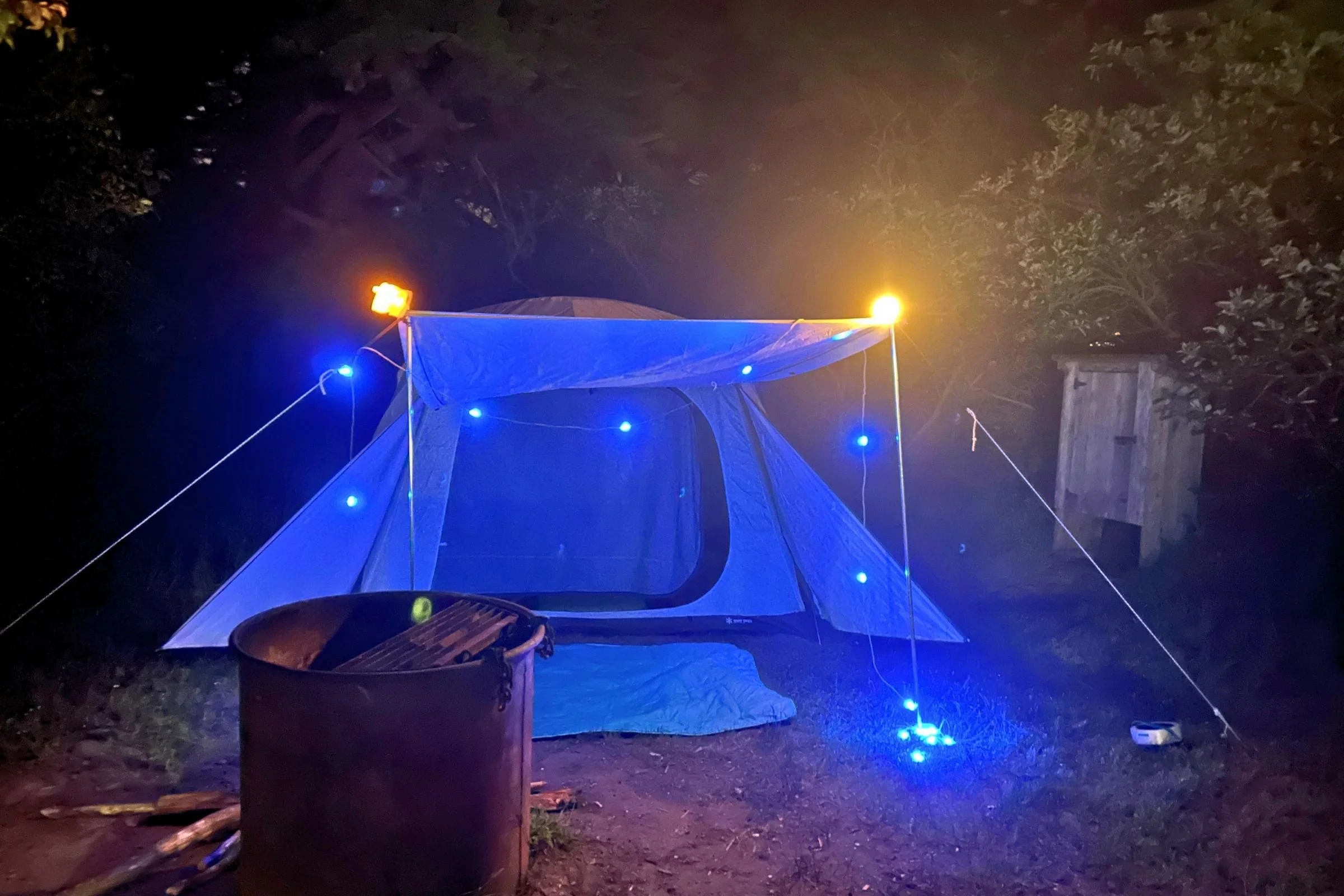 BioLite Luci 44' Solar String Lights cast blue and amber light around a camping tent.