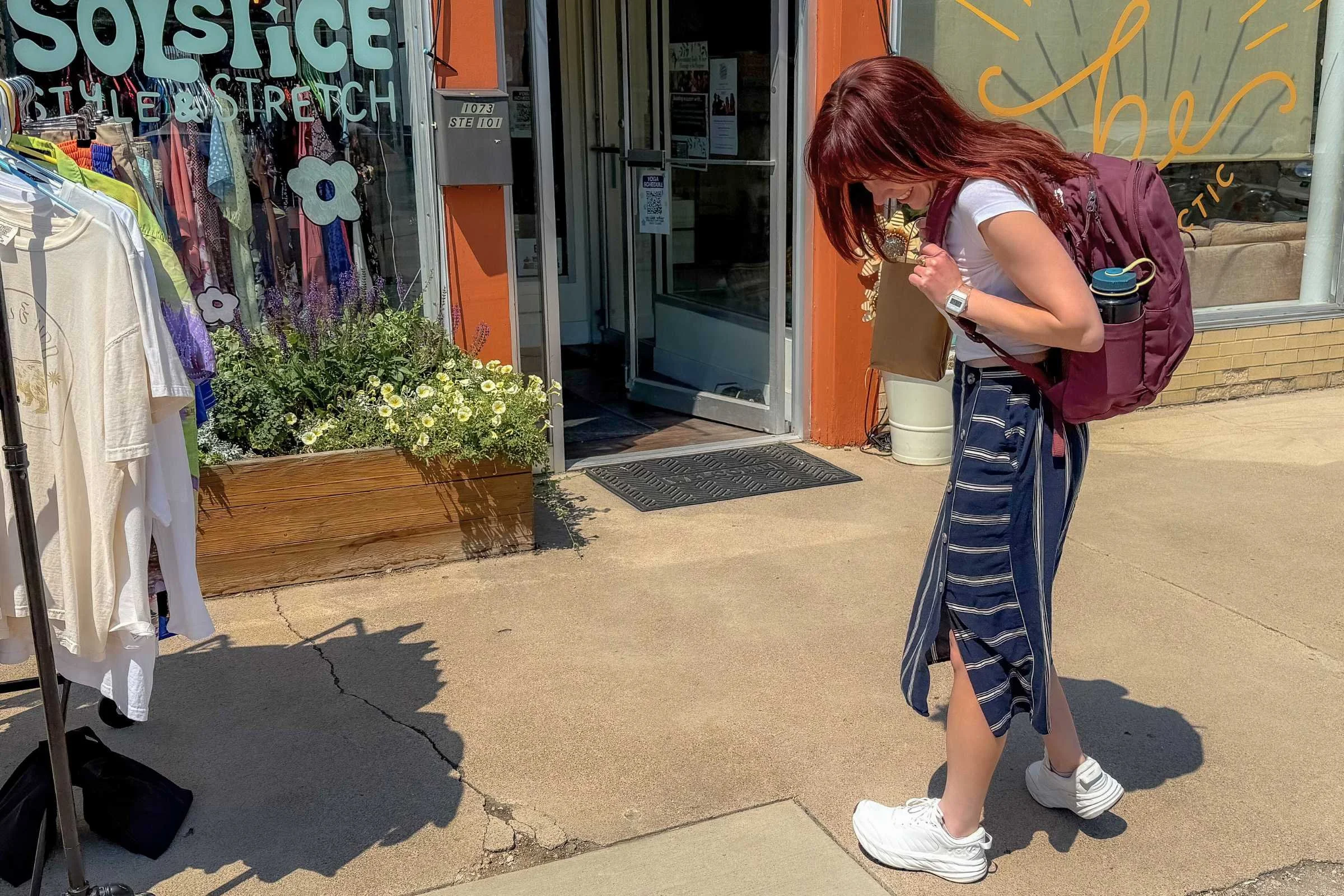 woman outside a clothing store wearing white hoka bondi sr shoes