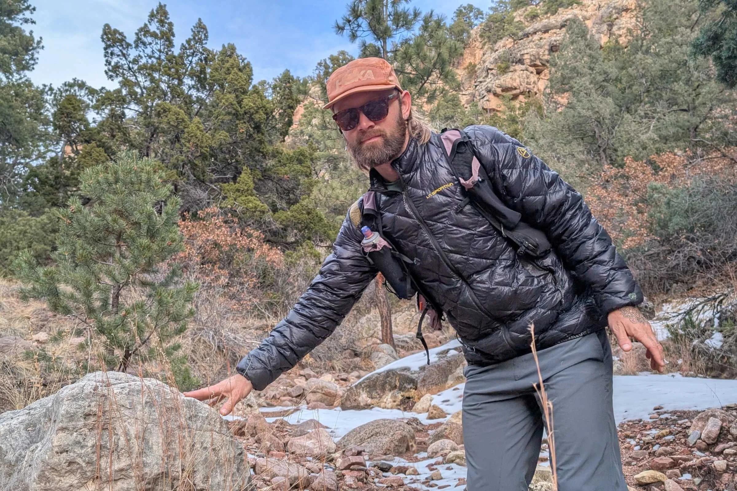 Hiker navigating rocky terrain in La Sportiva Lumina down jacket