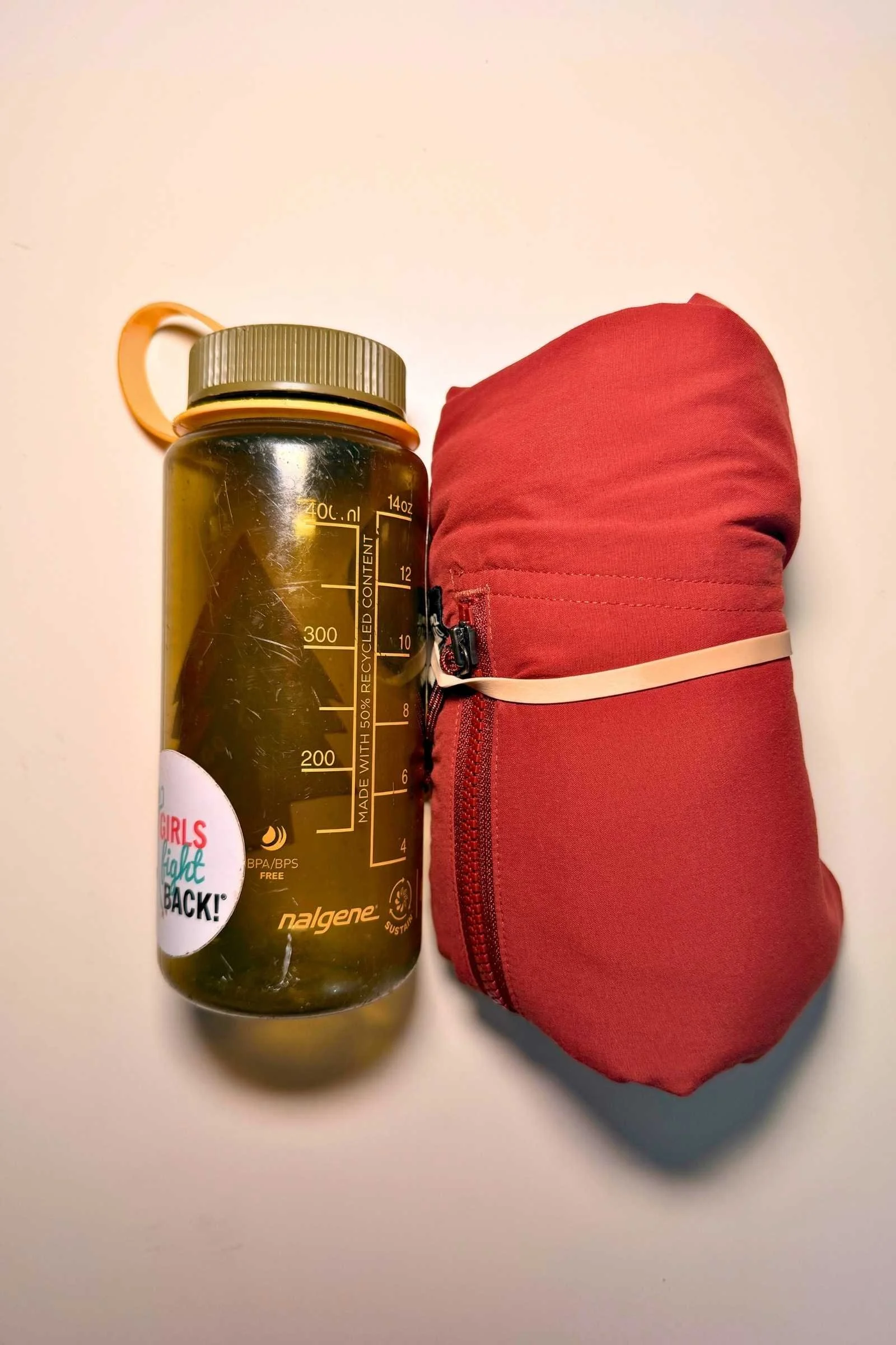 The REI Trailmade pants compressed into its own pocket next to a 1 liter Nalgene bottle for size comparison.