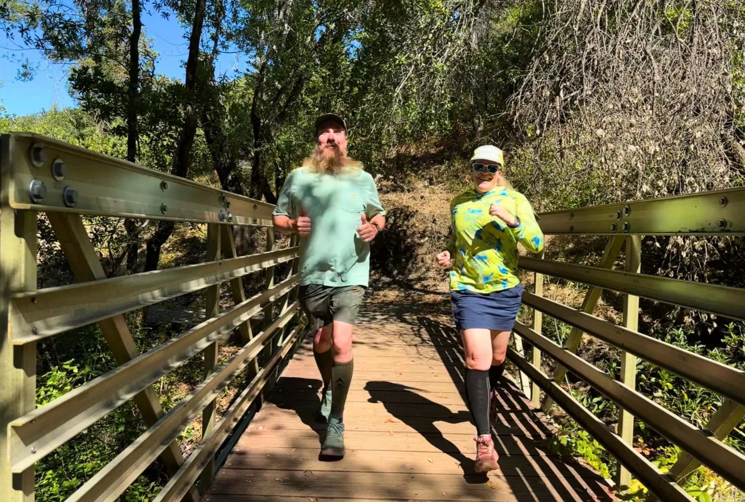 Two runners jogging along a wooden boardwalk trail