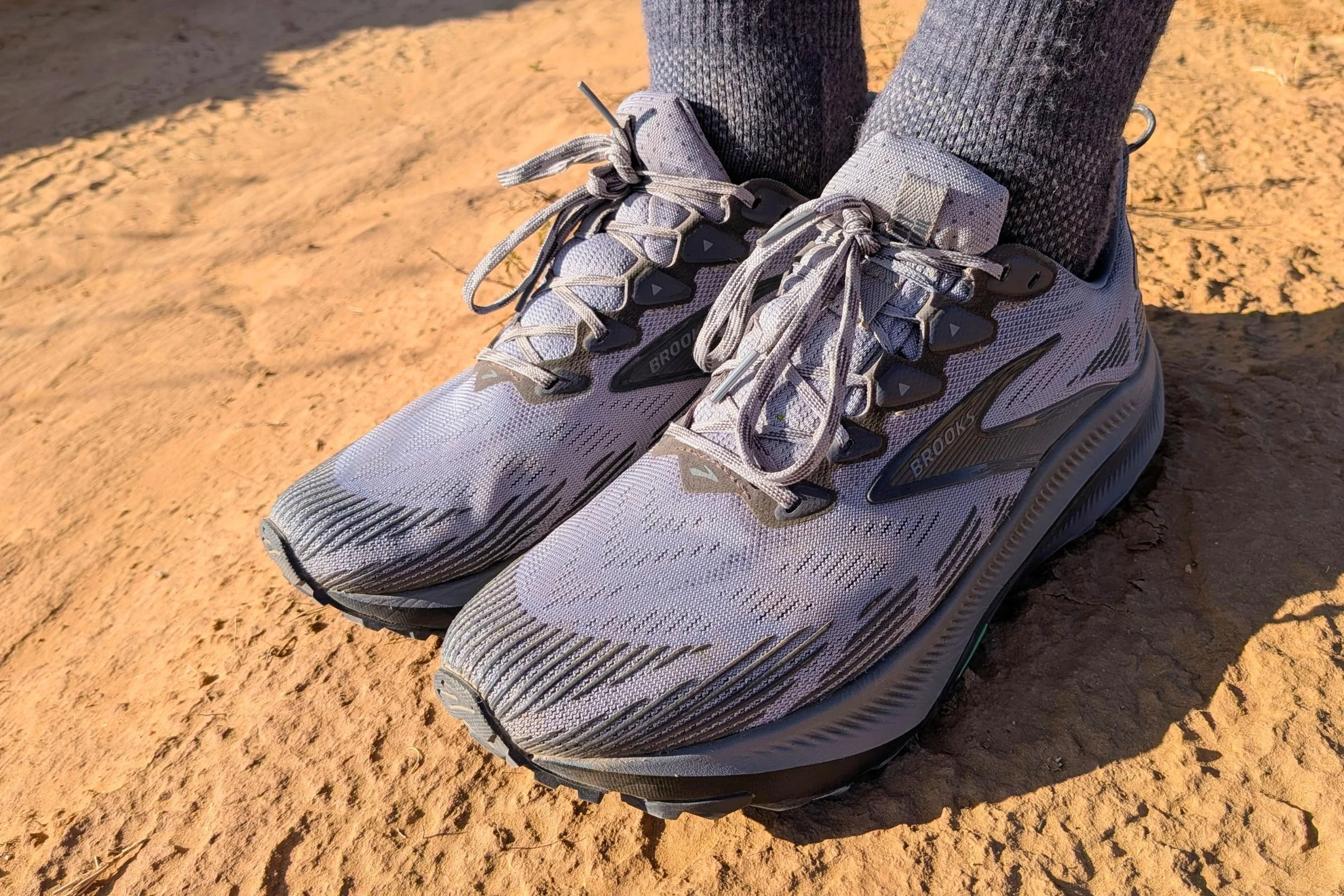 Close-up shot of Brooks Ghost trail running shoes on a dirt road.