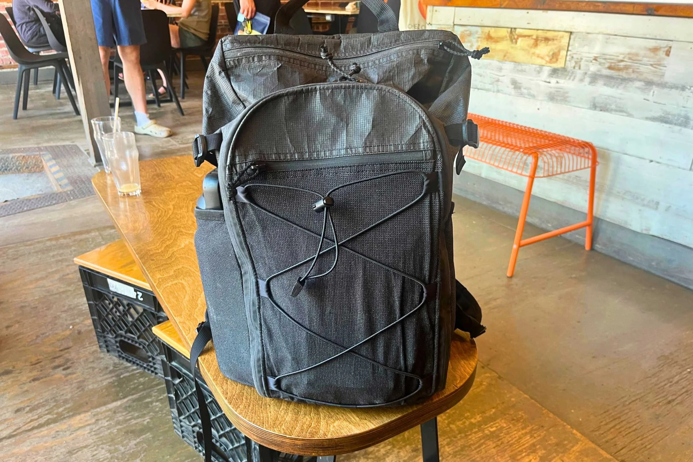 ULA Ultra Dragonfly 30L Adventure Travel Backpack on a wooden table inside a coffee shop.