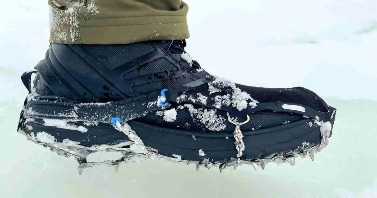 Closeup of person wearing hiking boots with traction devices over them on an icy surface