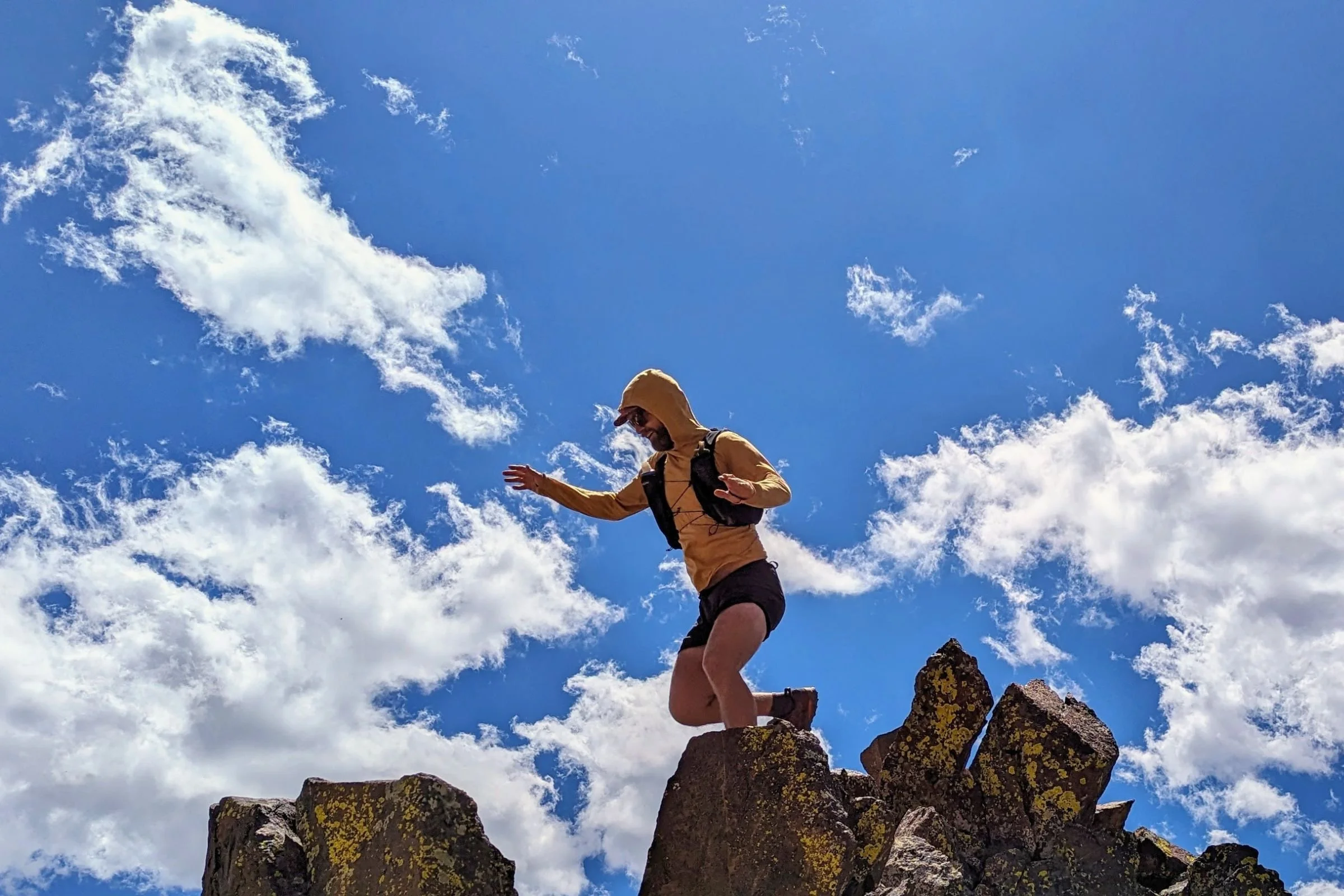 Man in Patagonia Strider Pro shorts jumping on top of a mountain.