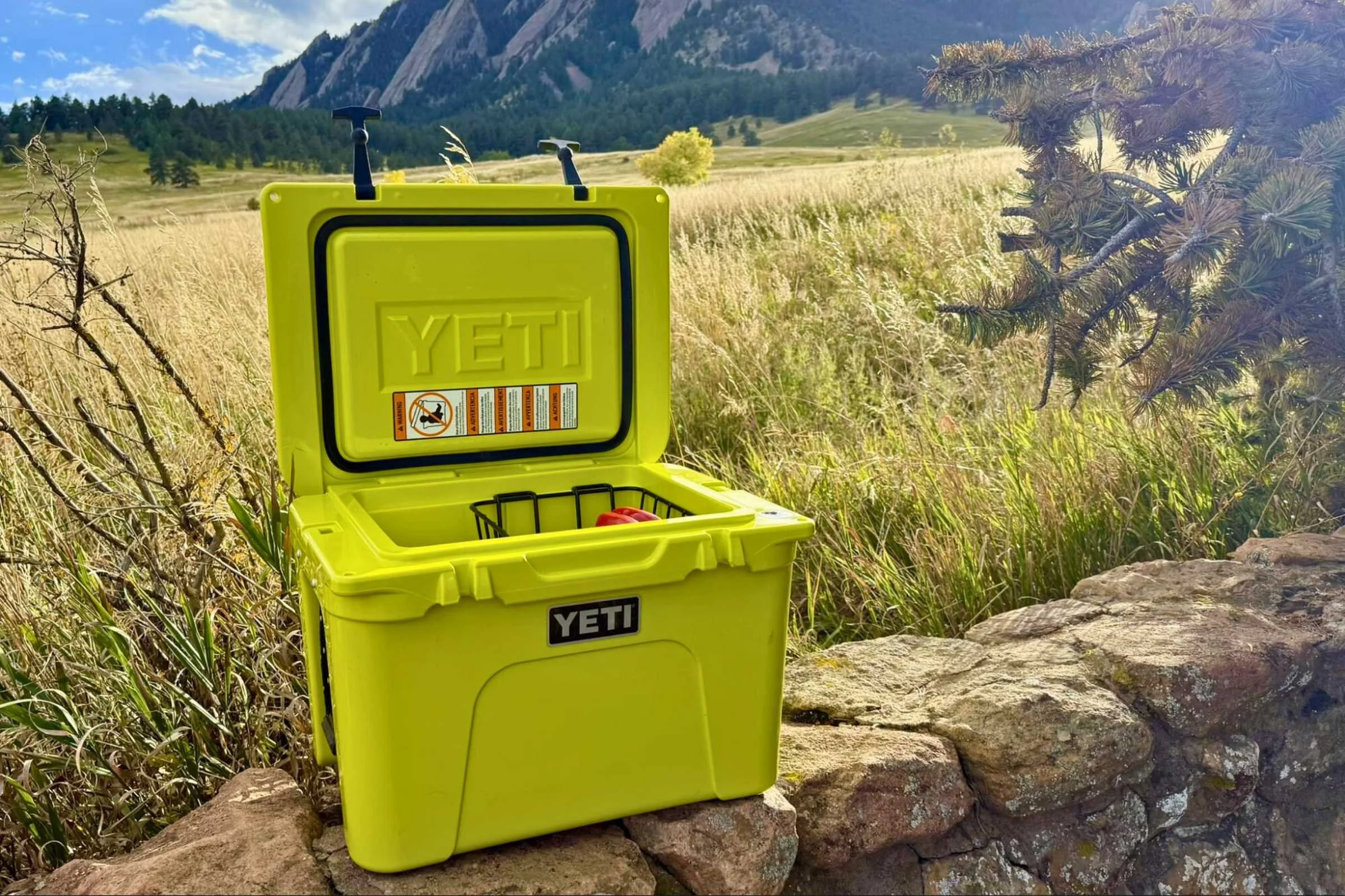 Open YETI Tundra 35 hero shot with a grassy field and the Flatirons of Boulder, CO in the background