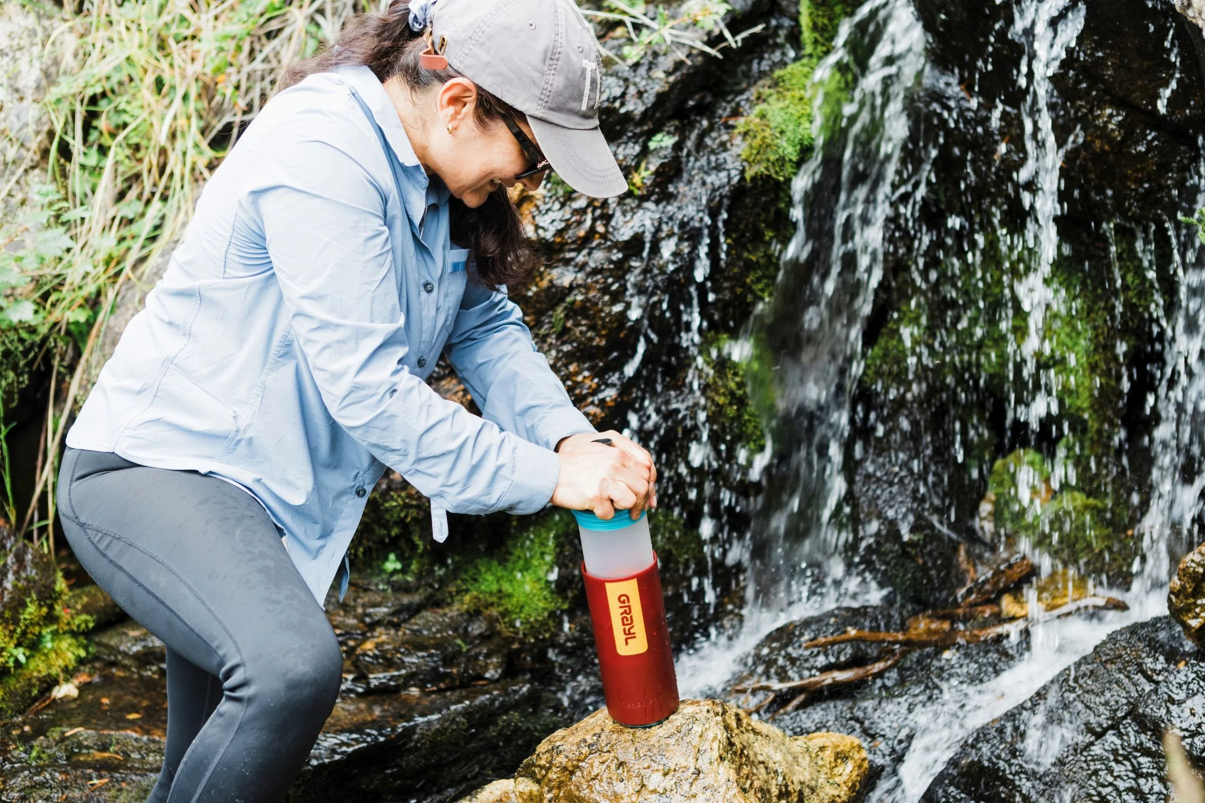 A woman pressing down on a Grayl GeoPress Purifier to filter water.